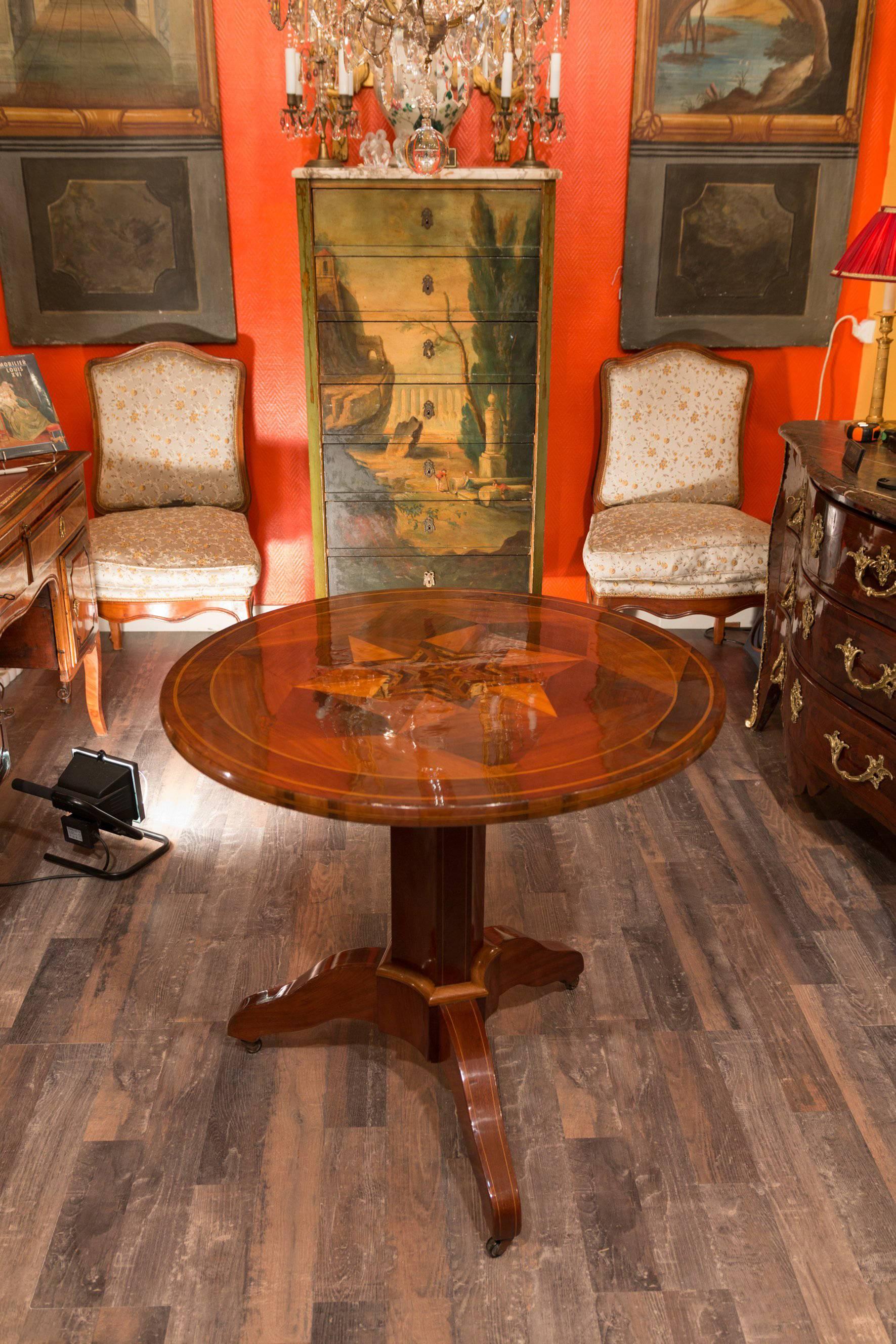 A gorgeous French pedestal round tilts top table, with lovely inlay of walnut, plum wood, Sycamore. The table is resting on a three-round footed pedestal base. 

Our table is in excellent condition. The underside of the table has clear and