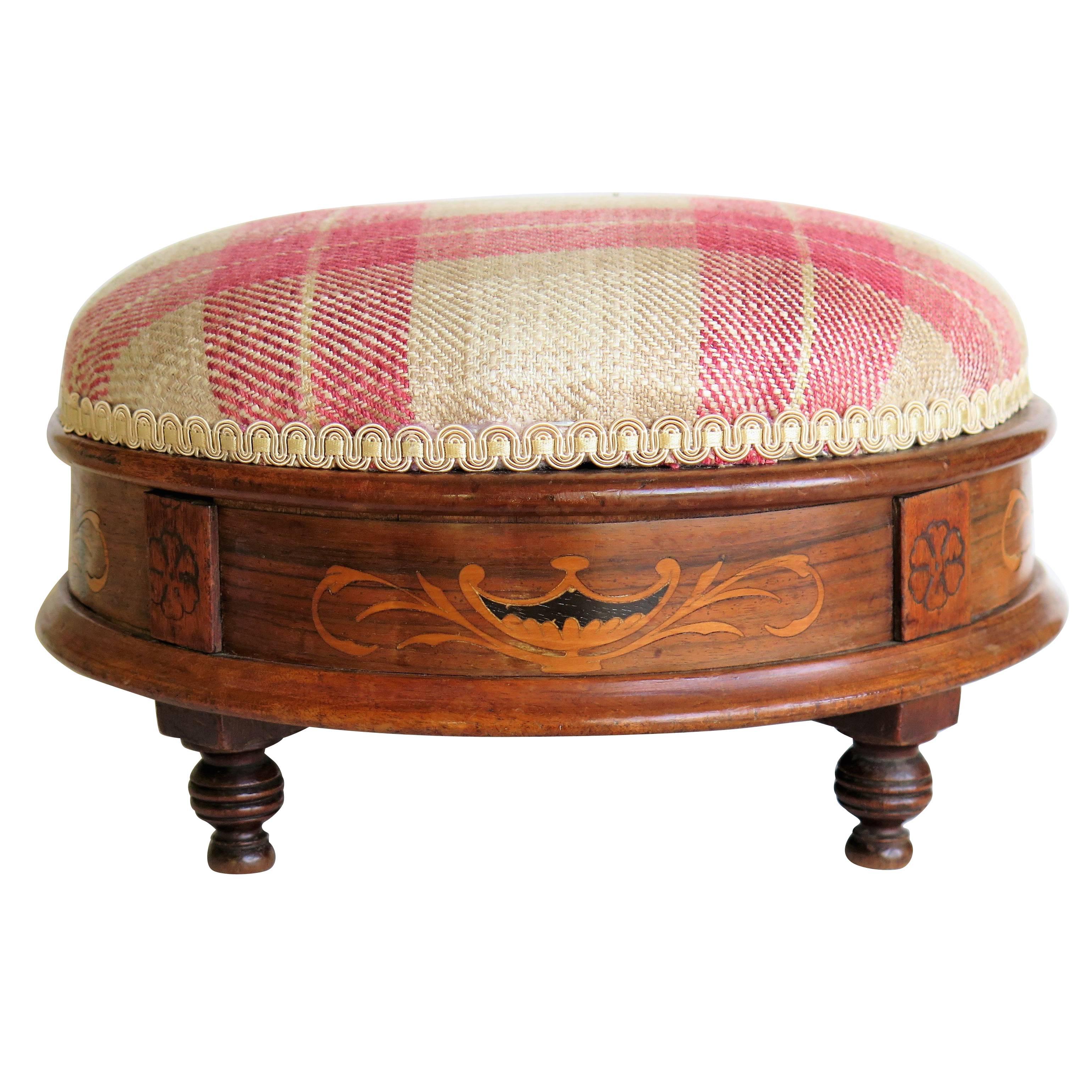 This is a very nice quality, English inlaid footstool, which we date to the early Victorian period, circa 1845.

The stool has a circular form and is made from walnut which has four sections of very decorative marquetry inlay to the sides. Each