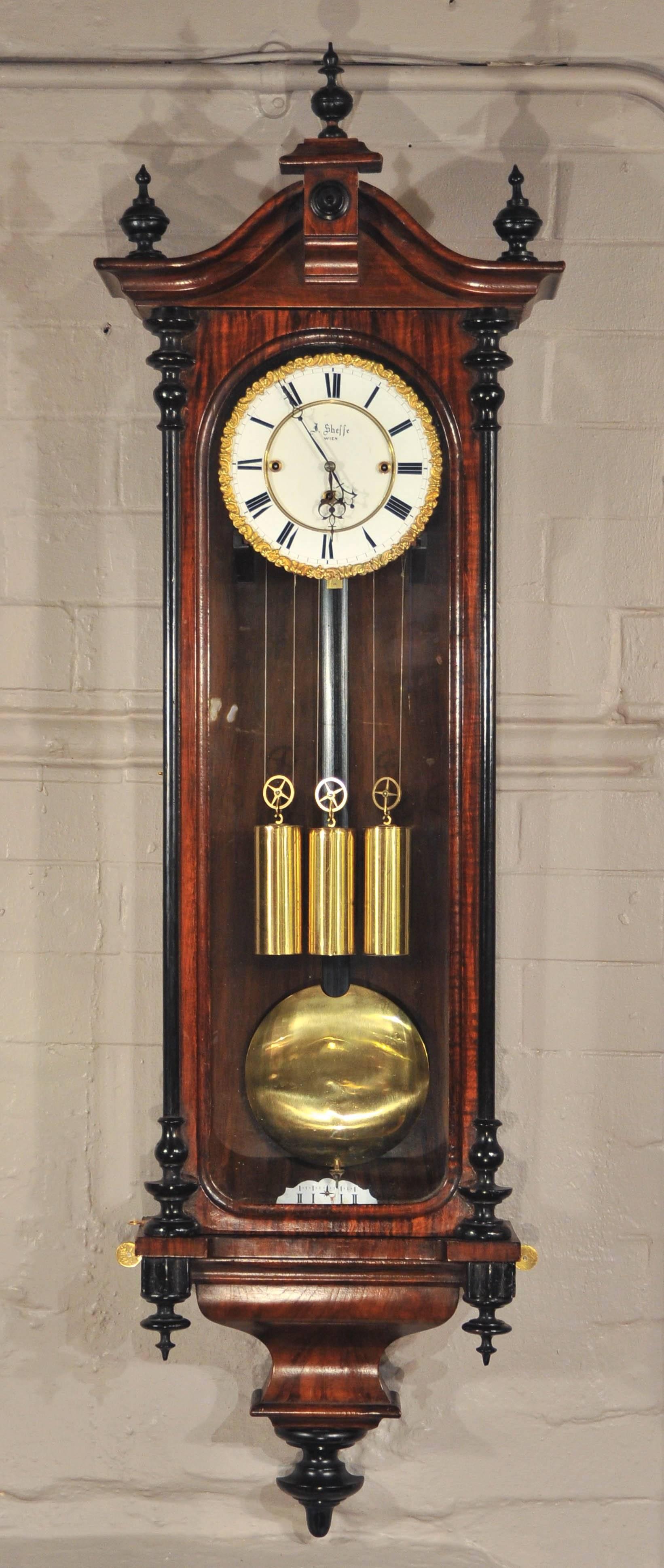 This fine clock case of simulated rosewood with ebonised columns and finials. The fully restored eight day duration triple train movement striking on two steel curled gongs every quarter hour. The enamelled dial with Roman numerals and finely cast