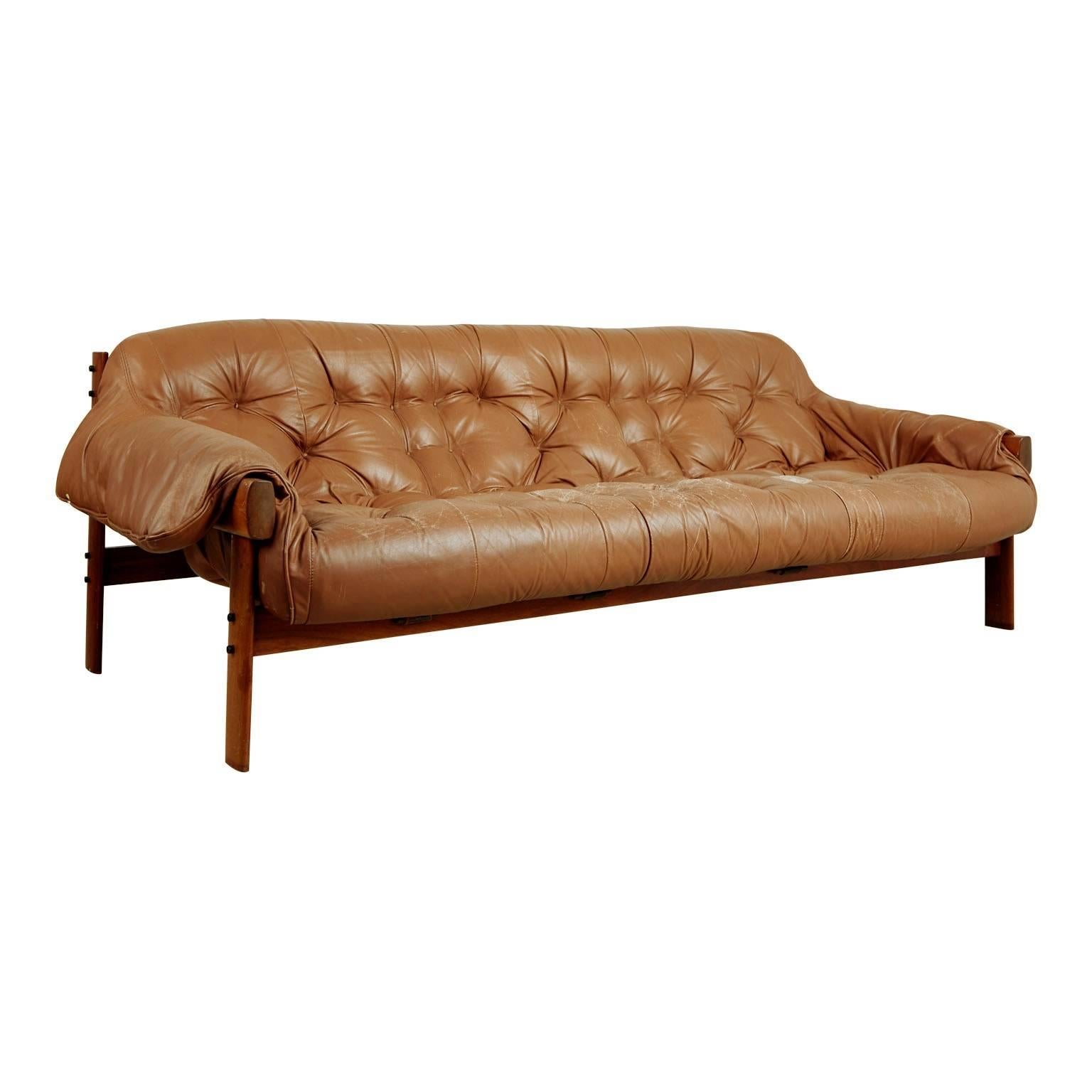 Wonderfully distressed brown leather sofa by Brazilian designer Percival Lafer for Lafer MP in 1961. Featuring a solid rosewood frame with beautiful grain that supports the natural leather straps which the tufted brown leather cushion rests on. The