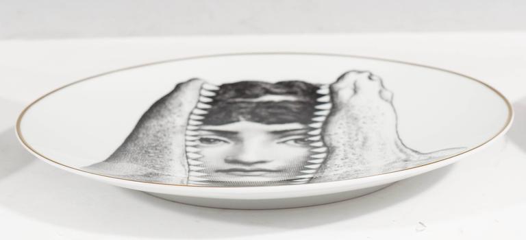 This arrangement of 12 porcelain plates, by Italian designer Piero Fornasetti for Rosenthal, from the 'Temi e variazioni' (“Themes and Variations”) collection, each portrays a highly unique surrealist variation of the image of renowned soprano
