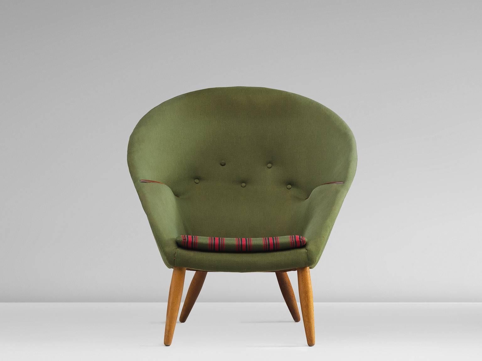 Easy chair, wool and teak, Denmark, 1953.

This round and comfortable armchair is designed by Nanna Ditzel. The chair features four thick legs that become smaller towards the top and bottom. The shell of the seat is round with a flat bottom. The