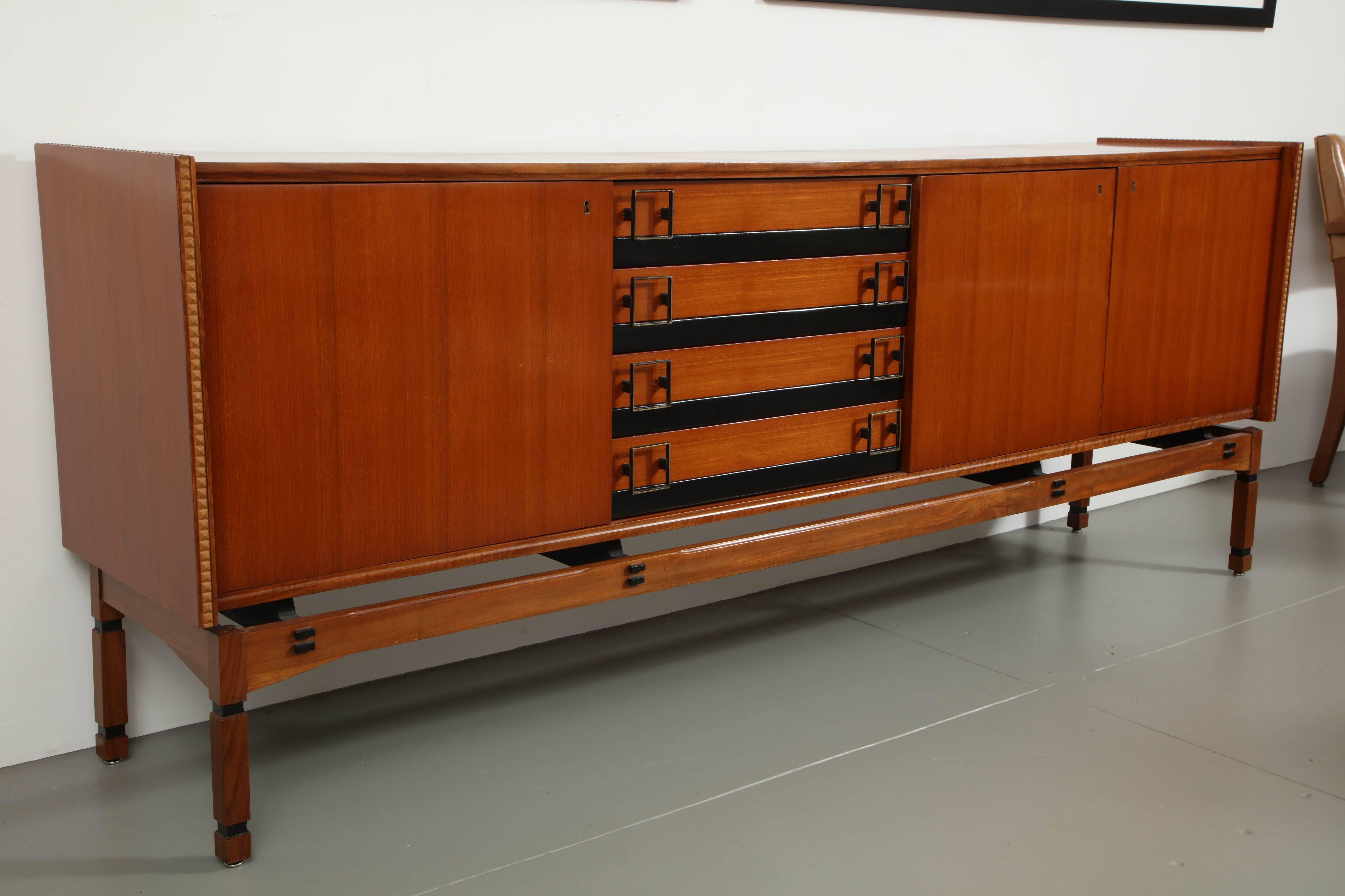 Mid-20th century teak sideboard, three doors, ebonized banding on four drawers, base joined by square legs

Italian, circa 1960.