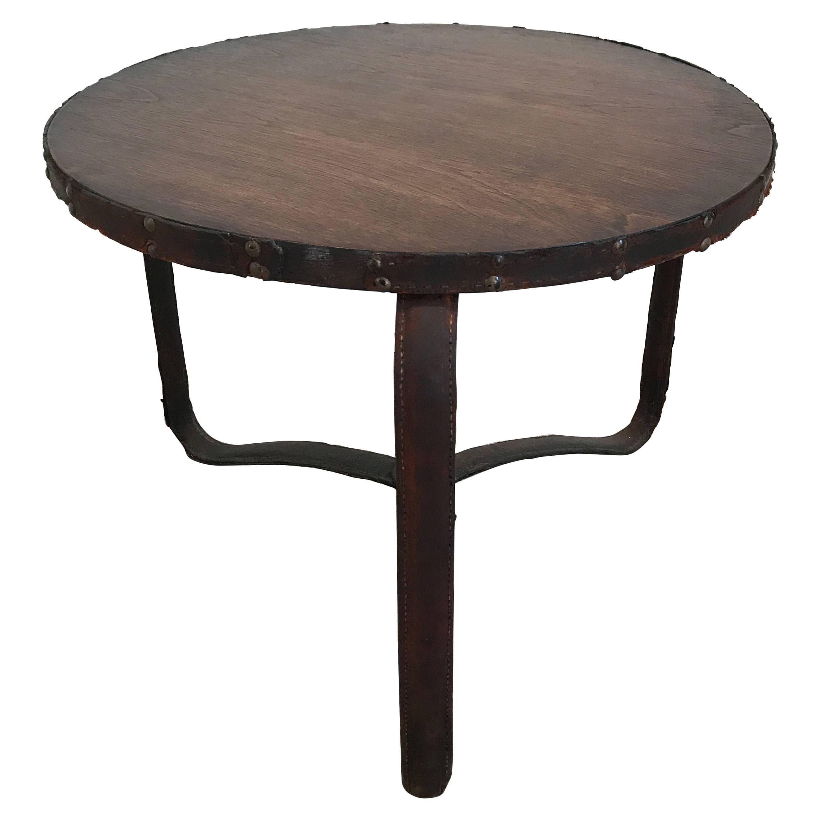 An early Jacques Adnet stitched leather table with oak top. Wonderful vintage example with distressed leather and few losses. The top has been lightly restored as well as reinforcing the leather.