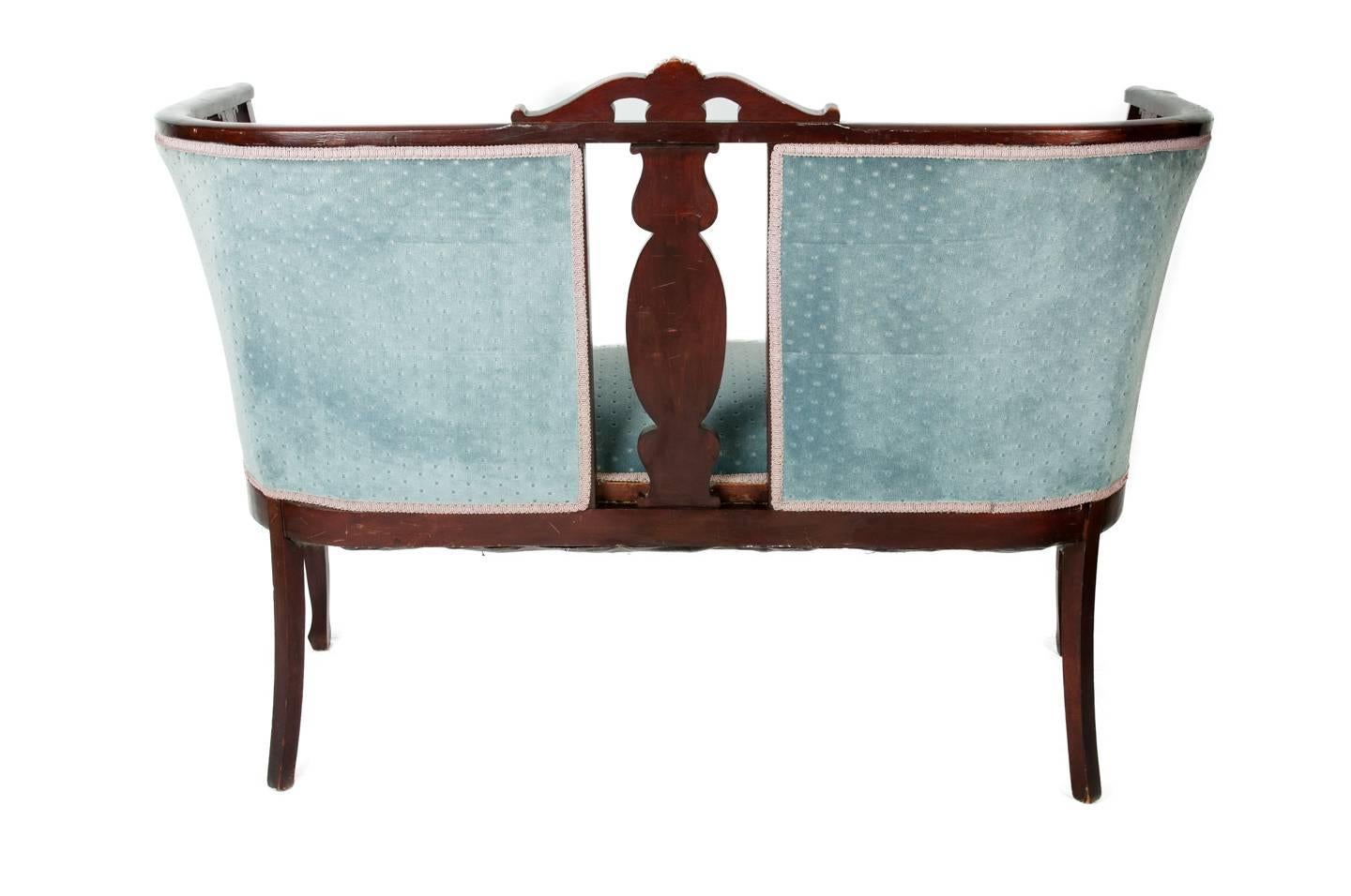 Victorian-style mahogany settee upholstered in turquoise velvet with tufted back.