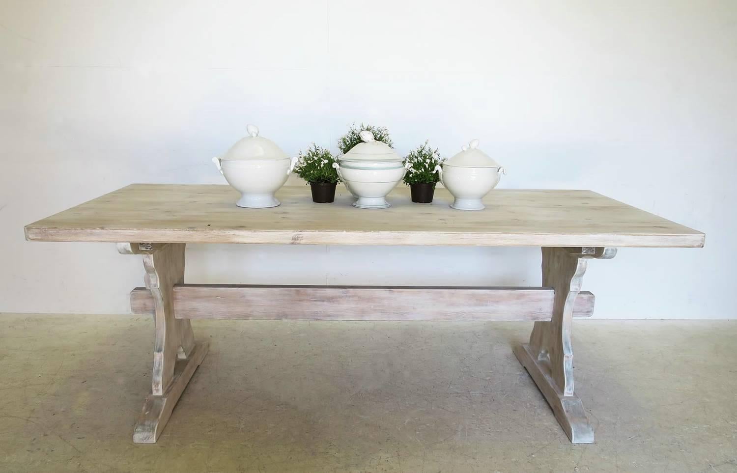 A Swedish pine trestle style dining table with central stretcher and beautifully shaped sides. This Classic table has a beautiful lime washed finish and the top is made from one solid piece of wood. This is a sturdy farm table that seats eight and