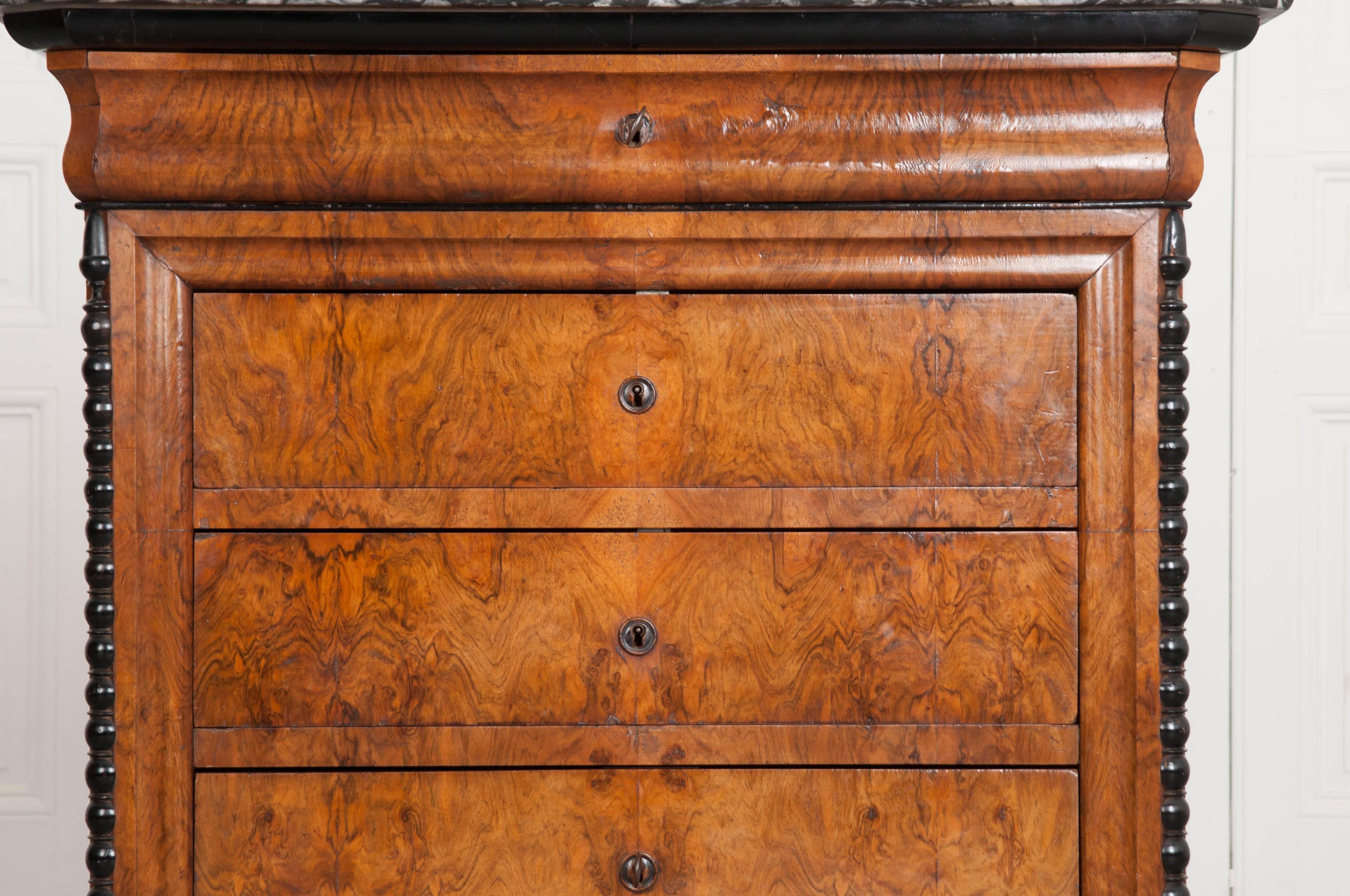 A handsome burl walnut Louis Philippe four-drawer commode from 19th century, France. The commode is smaller in stature, but big on beauty. The black fossil marble top is exceptional, with oysters visible, frozen in time. The marble-top has canted