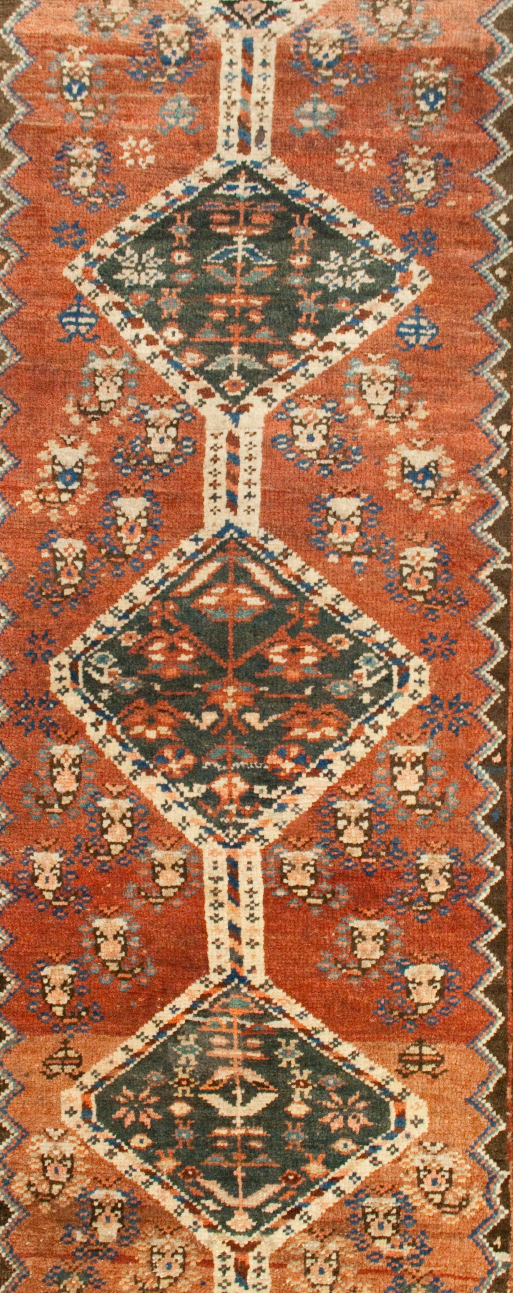 An early 20th century Persian Bidjar runner with ten diamond medallions on a variegated crimson field surrounded by multiple contrasting geometric and floral borders.
