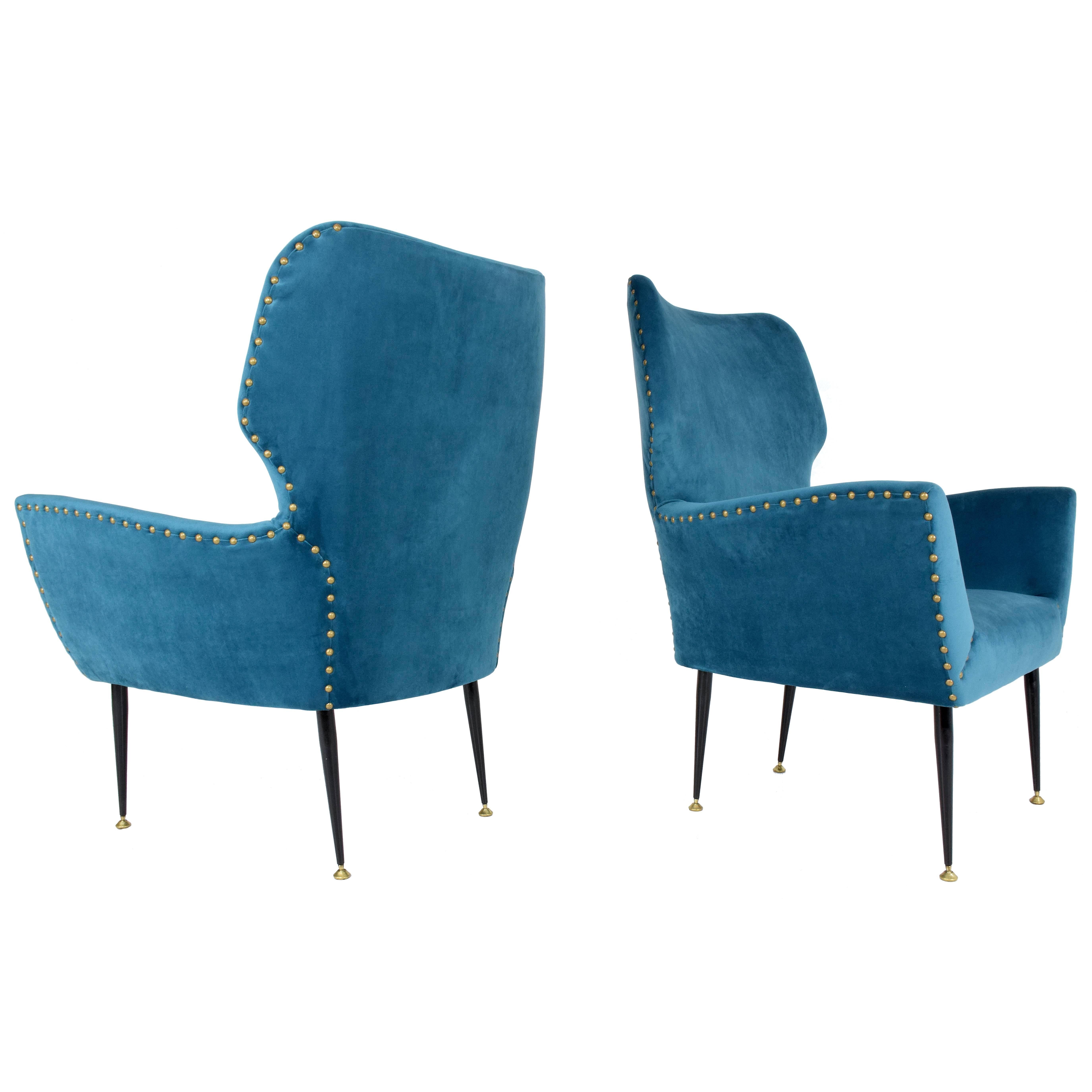Pair of 20th century vintage Italian armchairs with a curved silhouette frame and tapered steel legs with polished brass endings. We have restored the chairs with blue velvet upholstery, new padding and nailhead trim.

This staple style of Italy's,