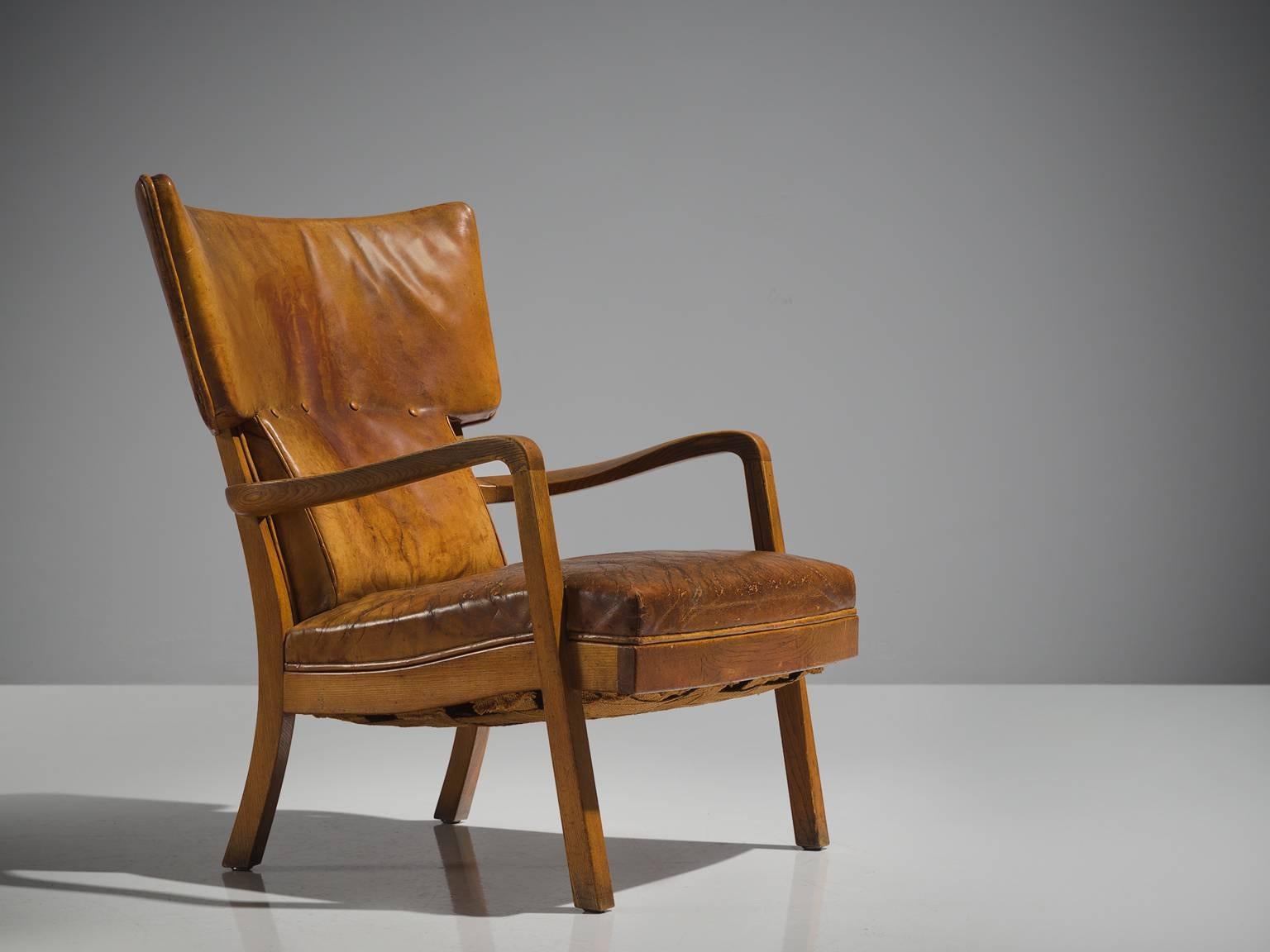 Peter Hvidt for Ludvig Pontoppidan, wingback chair, cognac leather and elm, Denmark, 1943.

This chair is made by Peter Hvidt for the reknown cabinetmaker Ludvig Pontoppidan. The chair has a strong, robust appearance thanks to the thick elm frame