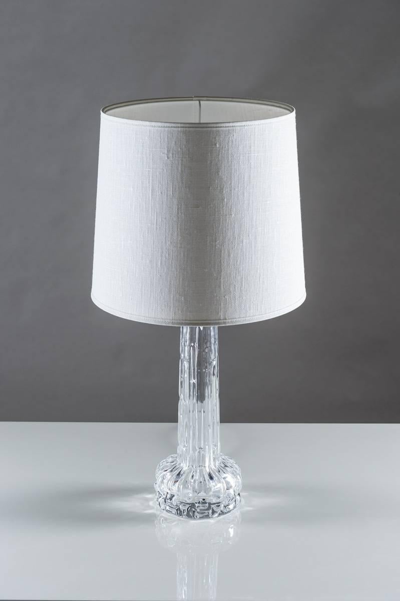 A pair of table lamps in crystal glass model RD by Carl Fagerlund for Orrefors, Sweden. The base is made of crystal glass and reminds of frozen water. The chrome details add to the feeling of frost and ice that is significant for the