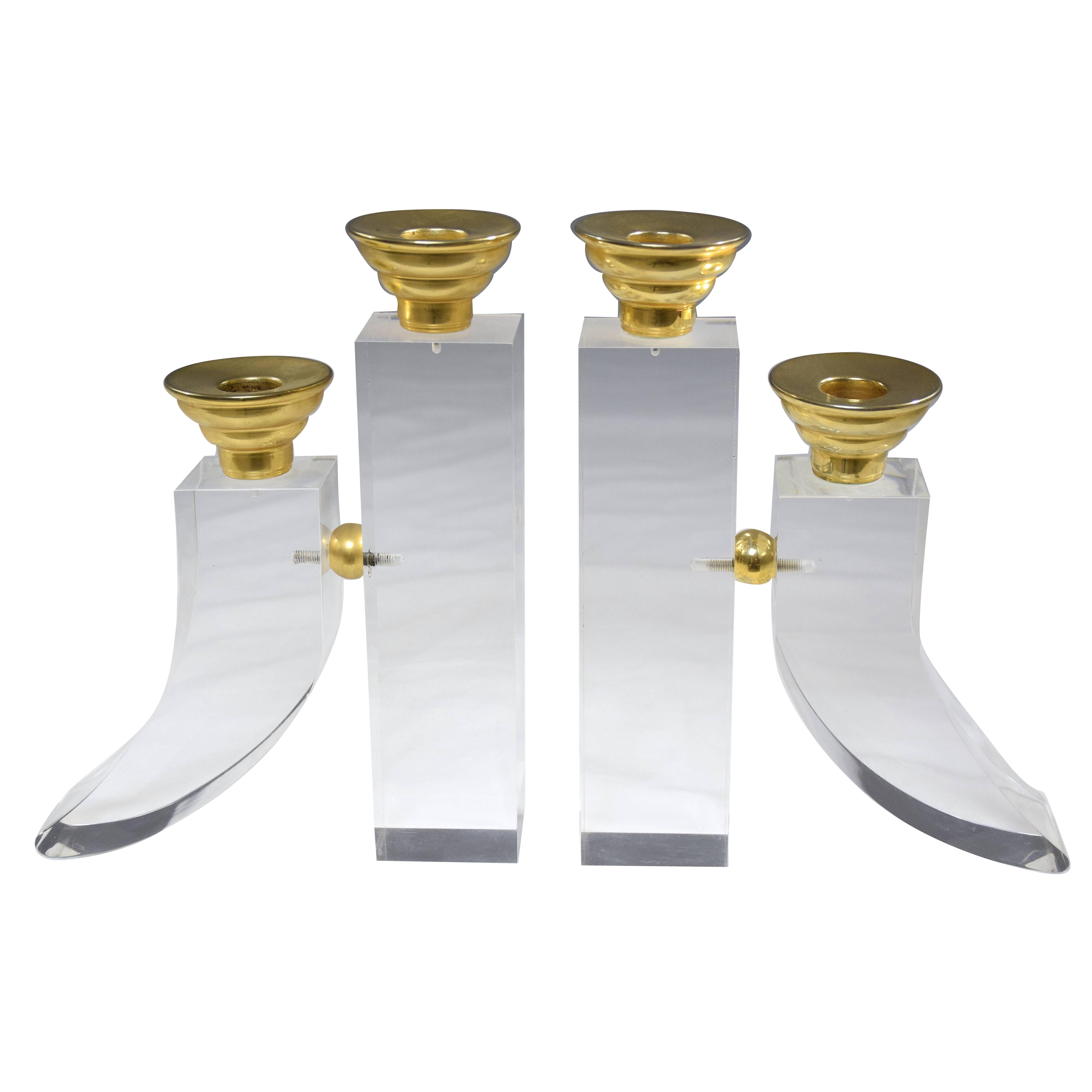 Pair of French 20th century vintage candleholders or candelabra each containing two candlestick holders set in curved block Plexiglas designs with polished brass details. The symmetrical styles are perfect for adding decorative allure to any living