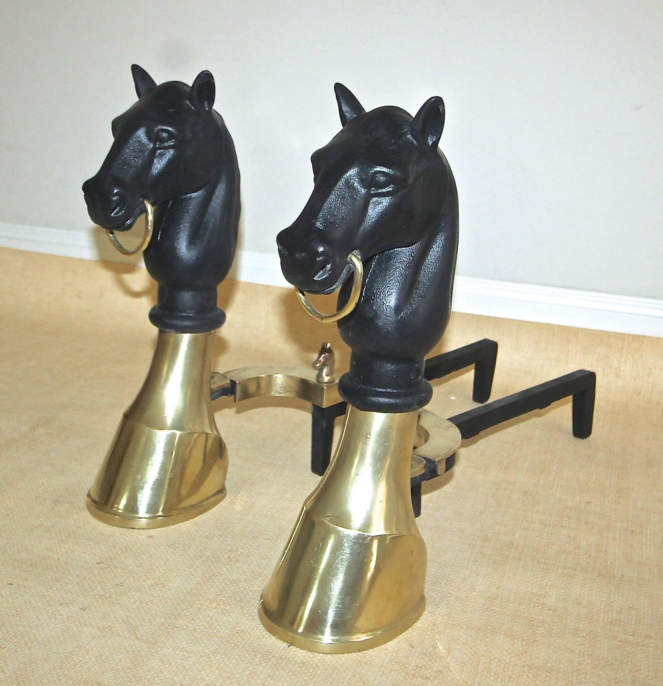 A very handsome pair of brass and cast iron andirons with a horse head and hoof motif and horse head finials at the base.