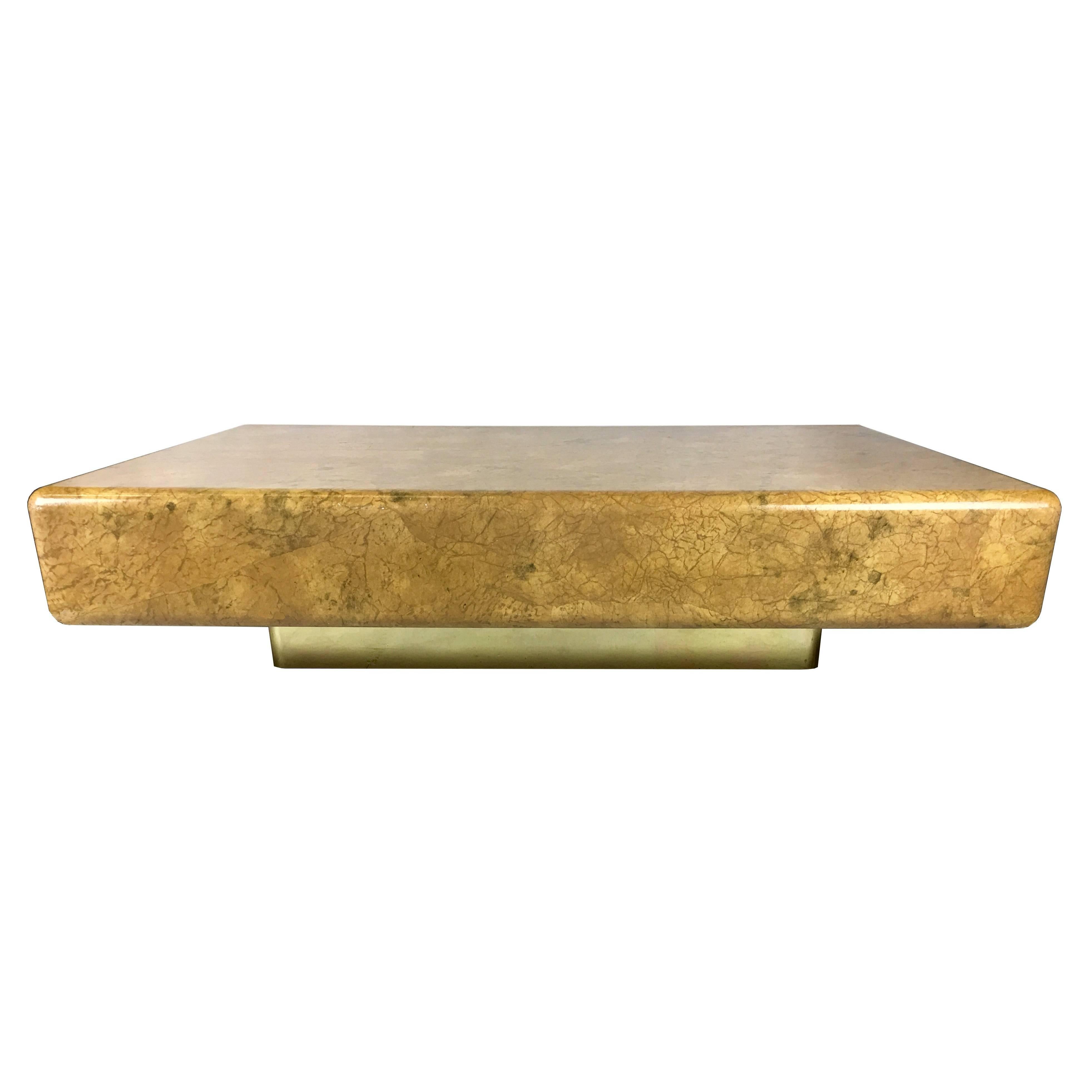 Large scale lacquered parchment coffee table raised on a brass clad recessed base in the style of Karl Springer's 80s designs. Top quality materials and workmanship.