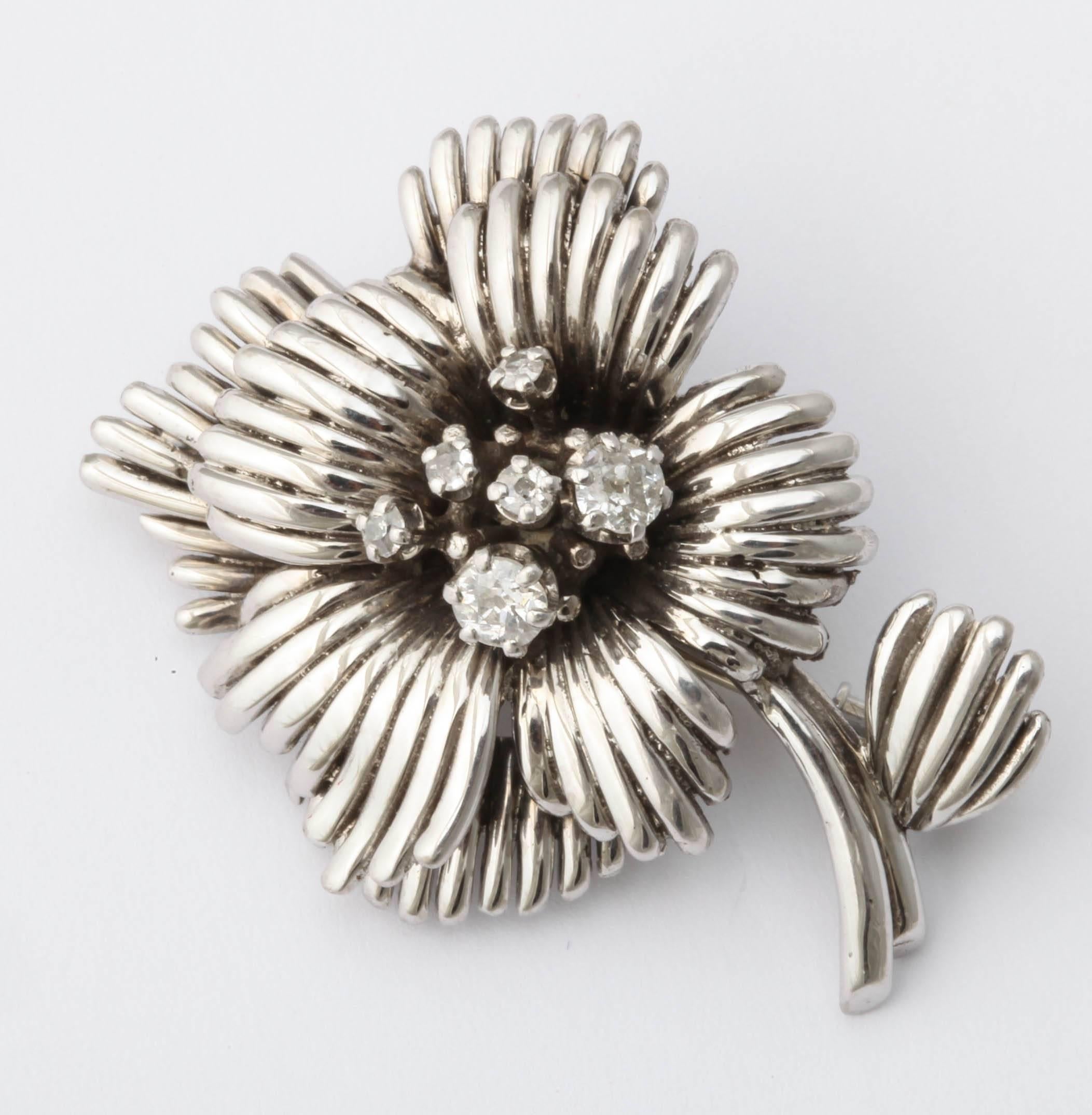 This Parisian 1950s diamond white gold pin is designed as an open flower in high relief, its pistil set with a cluster of six diamonds mounted in 18k white gold and platinum.

Paris, circa 1950s, with French hallmarks.

1 1/2 in. (3.8 cm.) long.