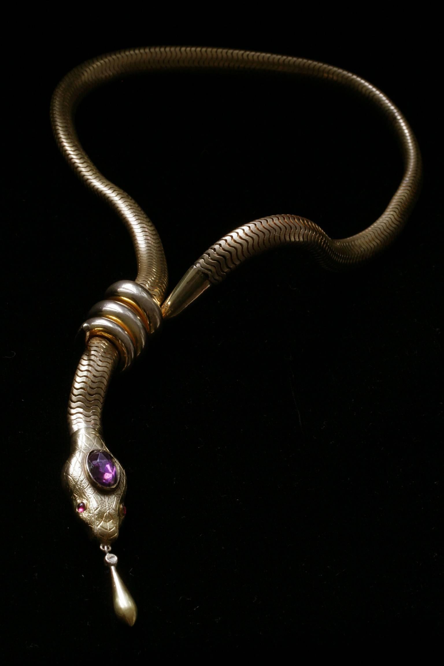 A strikingly constructed mid Victorian gold-filled serpent necklace. The textured serpent’s flexible body/chain goes through the triple-coiled tail, and the head/pendant screws into the chain. The handsome snake’s head has garnet paste eyes and a