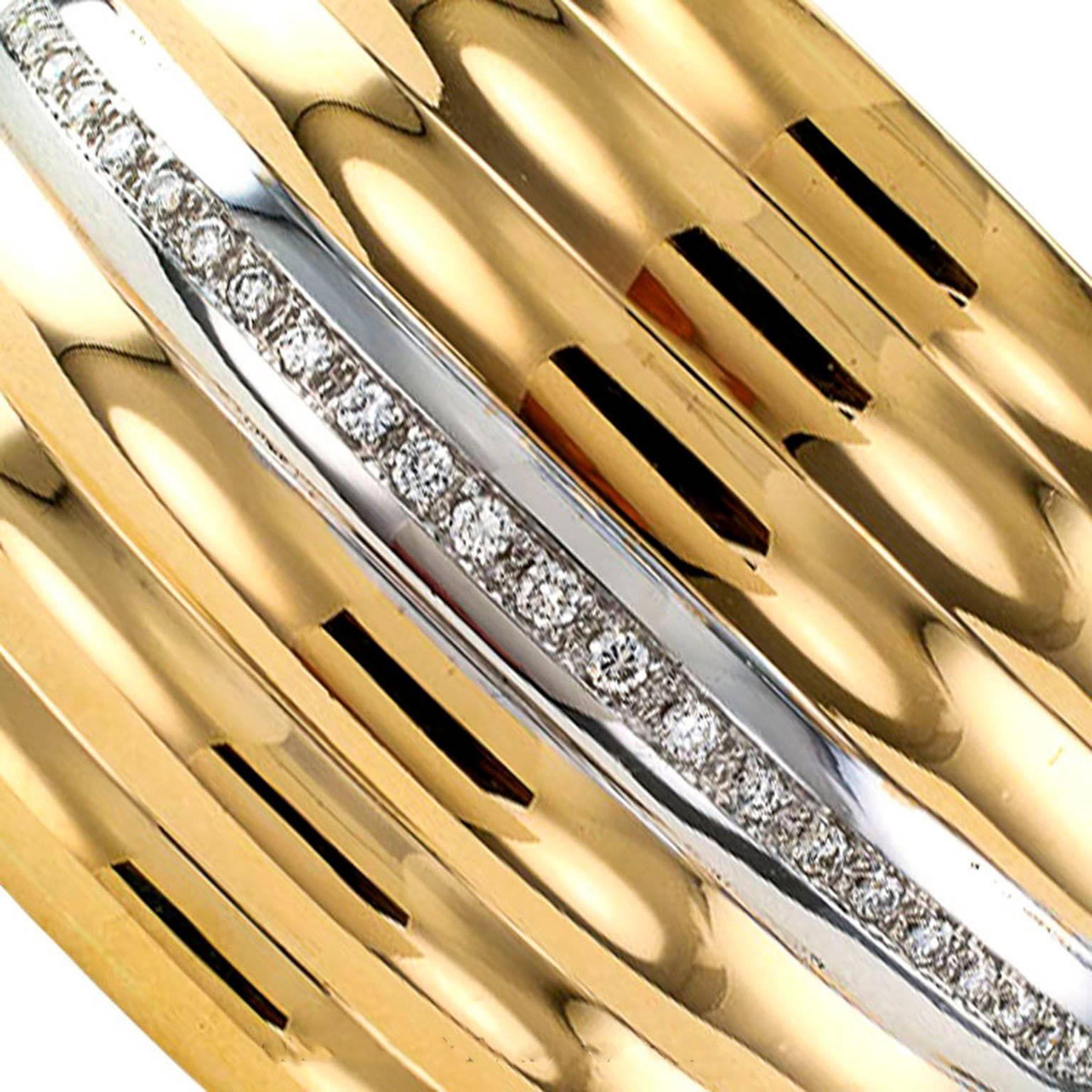 Contemporary Gold and Diamond Hinged Cuff Bracelet.

A wide two-tone 18-karat gold and diamond hinged cuff bracelet designed to create the illusion of seven rippling bands of brightly polished gold, the central band set with a course of twenty-seven