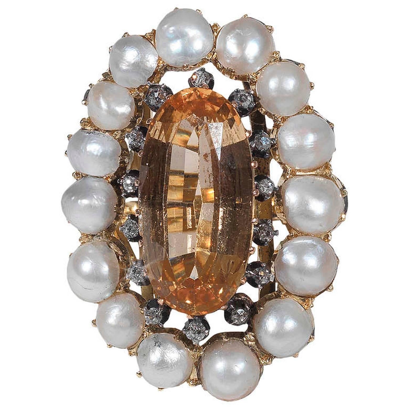 

The oval faceted topaz weighing approximately 9 carats cut down-set in between an half pearl cluster surround, mounted in yellow gold.

Circa 1800.

Weight 16.4 grams

Size 7
