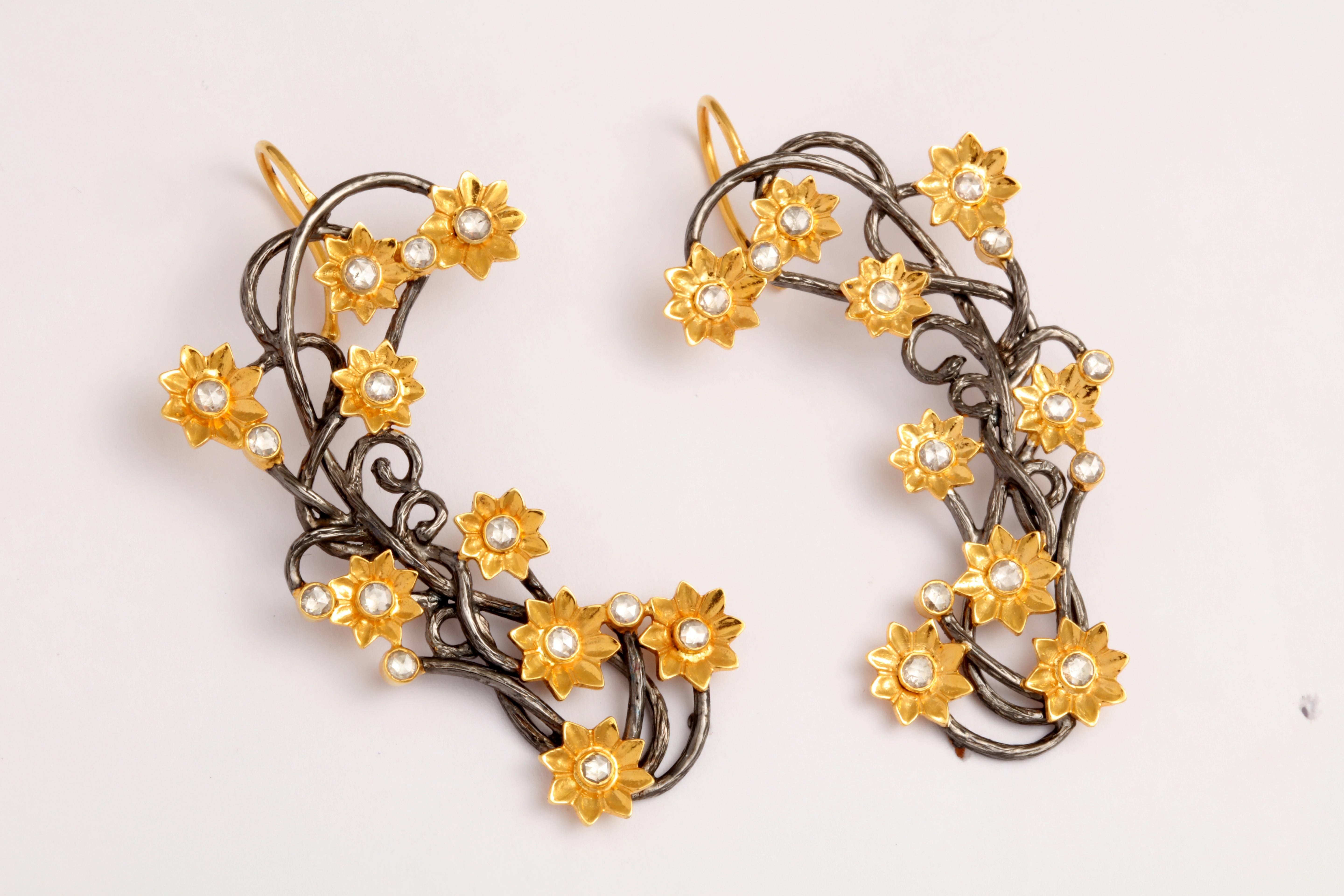A par of ear cuffs composed of rhodium plated sterling silver vines, 18kt yellow gold flowers and rose cut diamonds.There are 1.68 cts of diamonds.

Length: 3.00 inches
Width: 1.15 inches 
