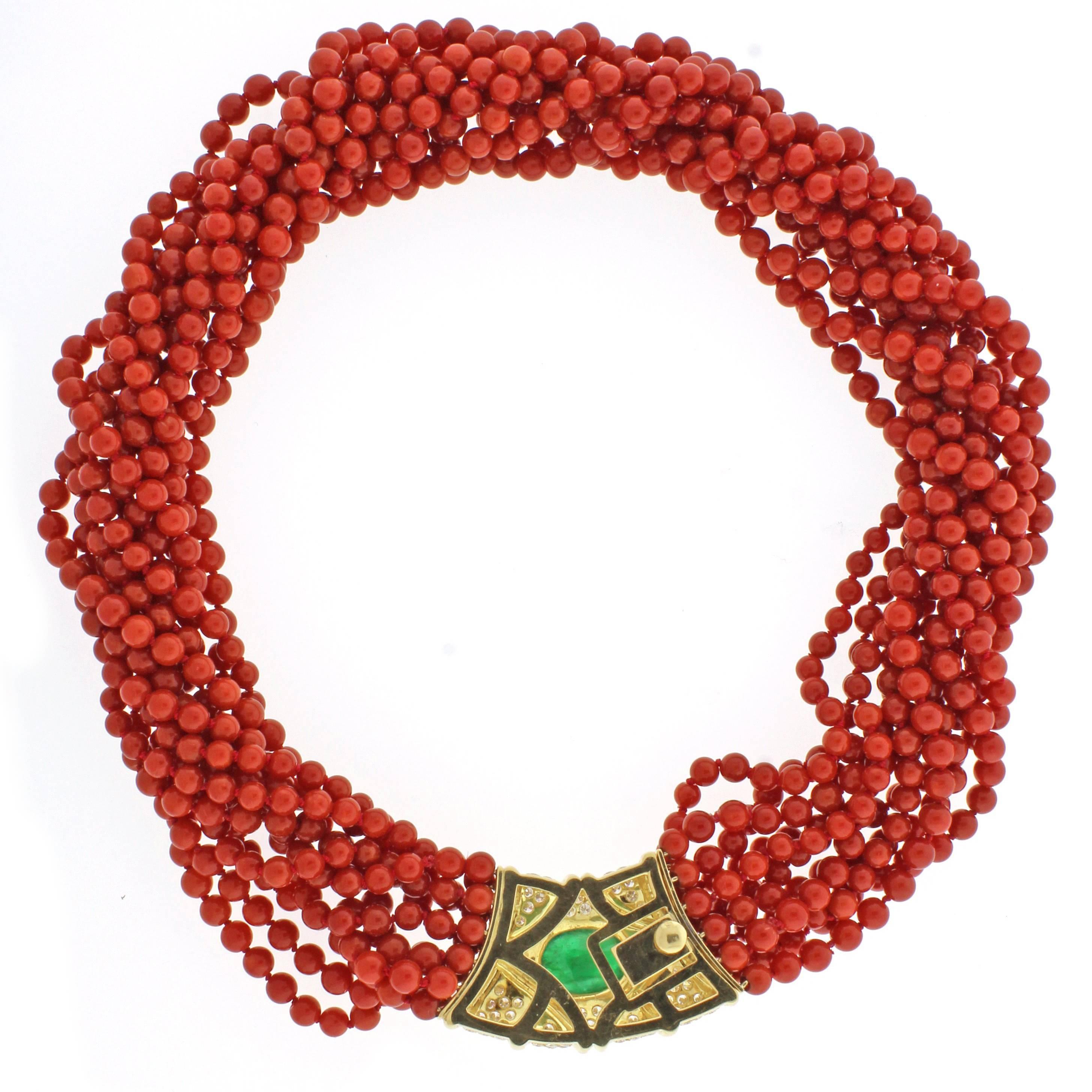 This stylish necklace is comprised of eleven stands of red 4.5-5mm coral beads with an impressive diamond and emerald clasp. The clasp contains 74 brilliant diamonds weighing  approximately 2.75 carats and a cabochon emerald weighing approximately