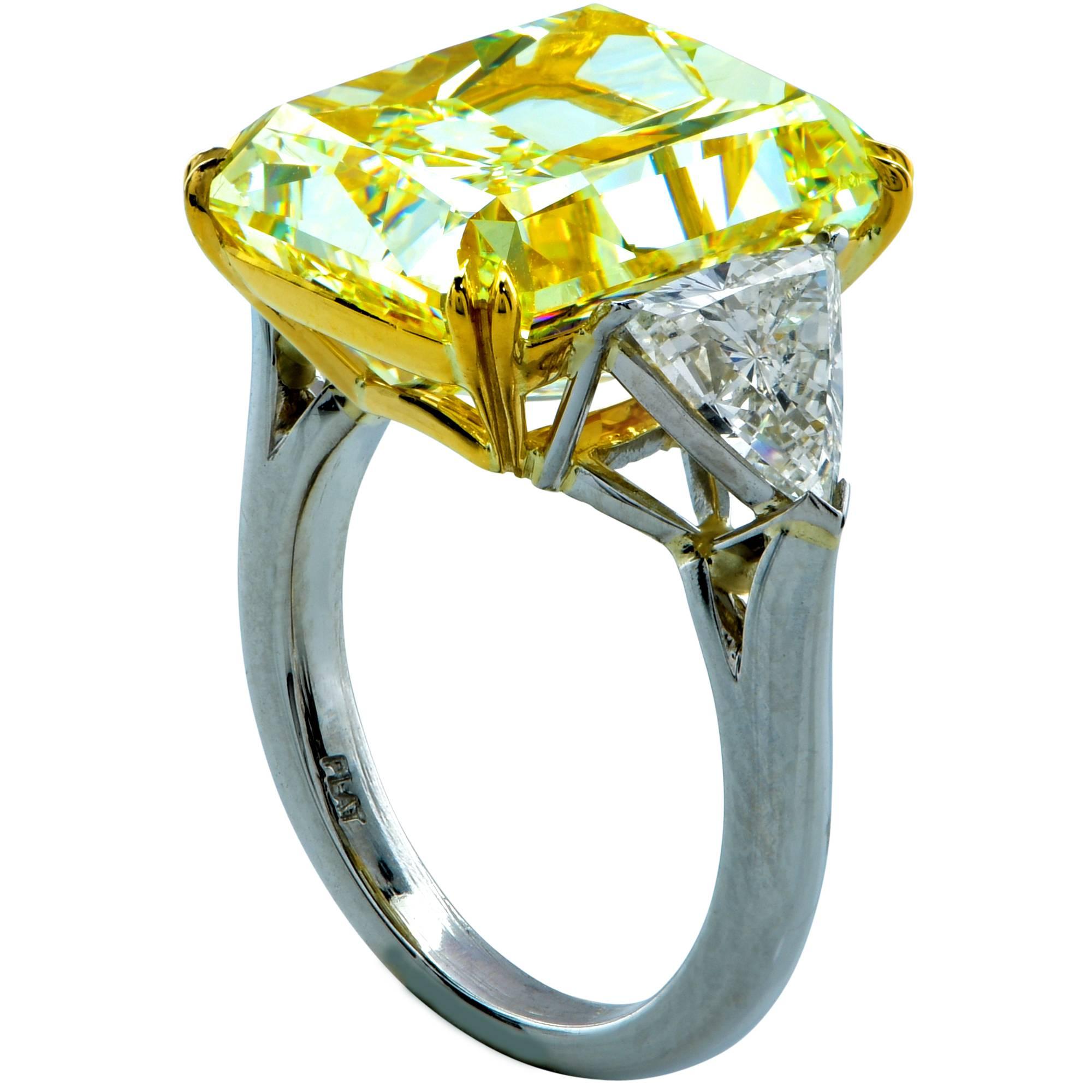 This alluring three stone diamond engagement ring features a GIA graded 14.20ct fancy light yellow radiant cut diamond with VS2 clarity. This beautiful diamond has incredible saturation of color and immaculate scintillation. It is masterfully