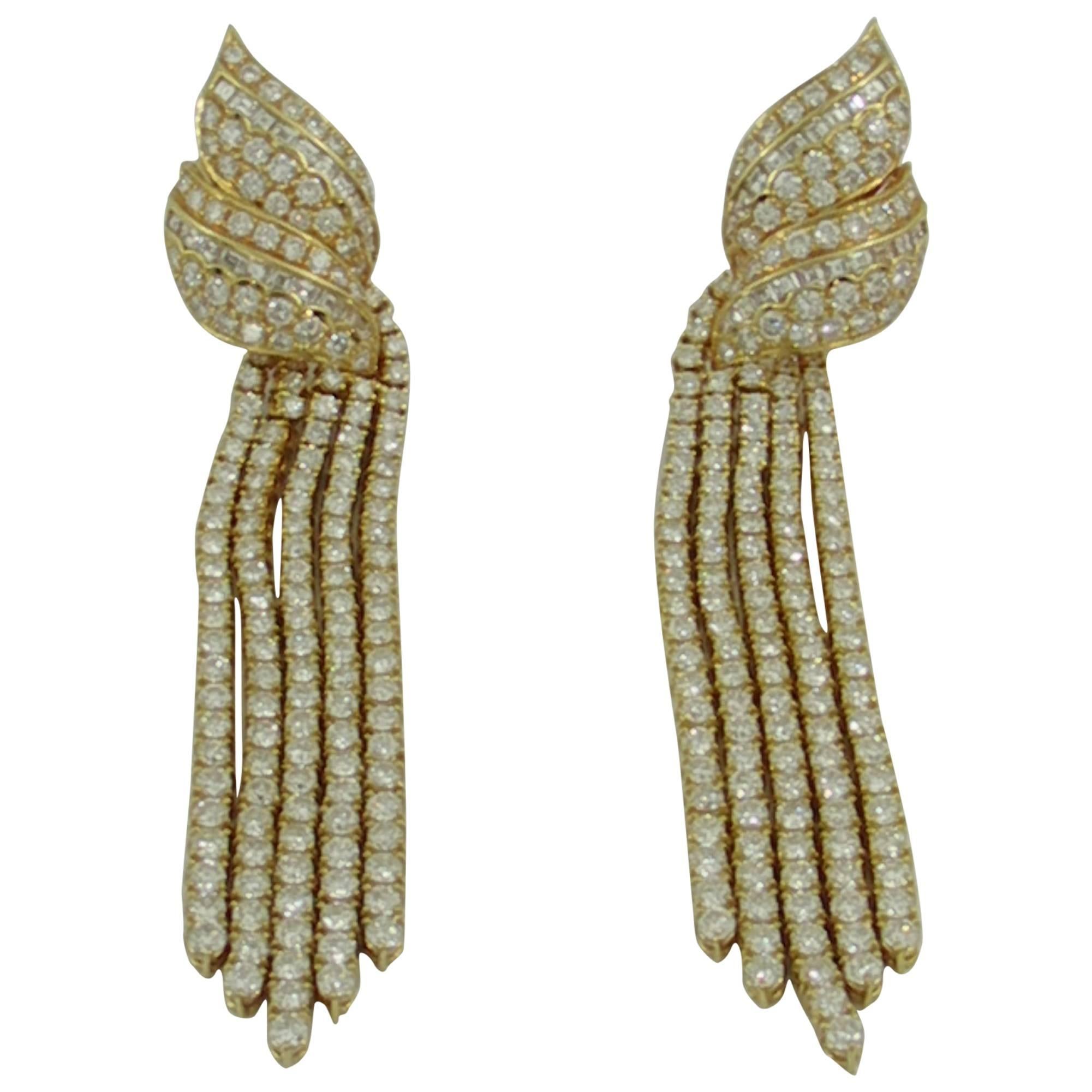 A dramatic pair of gold and diamond chandelier earrings, with double up-swept tops, and each bottom comprised of 5 tassels. Each glamorous earring measures 11/16 of an inch wide, by 3 3/4 inches long, and are set with a total of 19ct of round