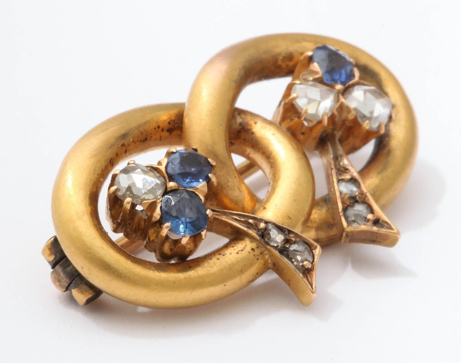 Rare Russian pin from the Romanov era, period of Tsar Nicholas II designed as a gold lover's knot, each loop set with a sapphire and diamond trefoil, its tapered stem set with rose diamonds.

By Vladimir Soloviev, St. Petersburg, 1899-1908.  

1 1/8