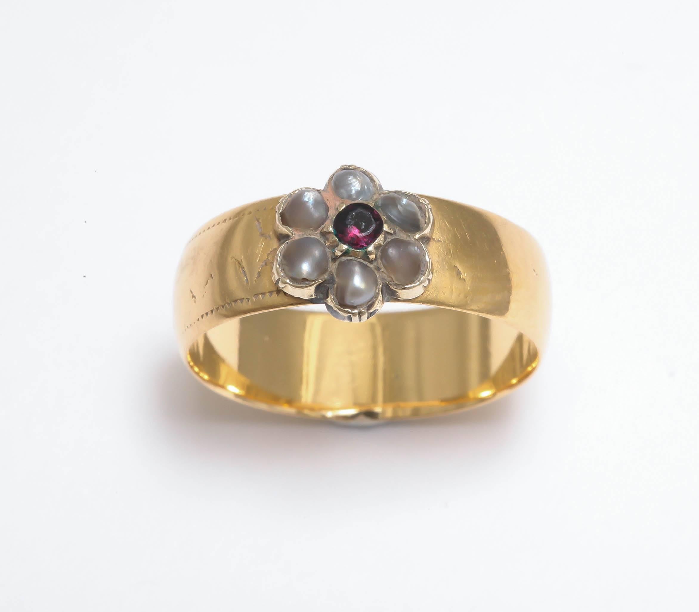 The Georgian or Victorian ring of classic daisy design, the smooth 18k gold band with a seed pearl and garnet flower.

Birmingham, 19th century, fully hallmarked.

Width of band: ¼ in. (0.65 cm); size 6.