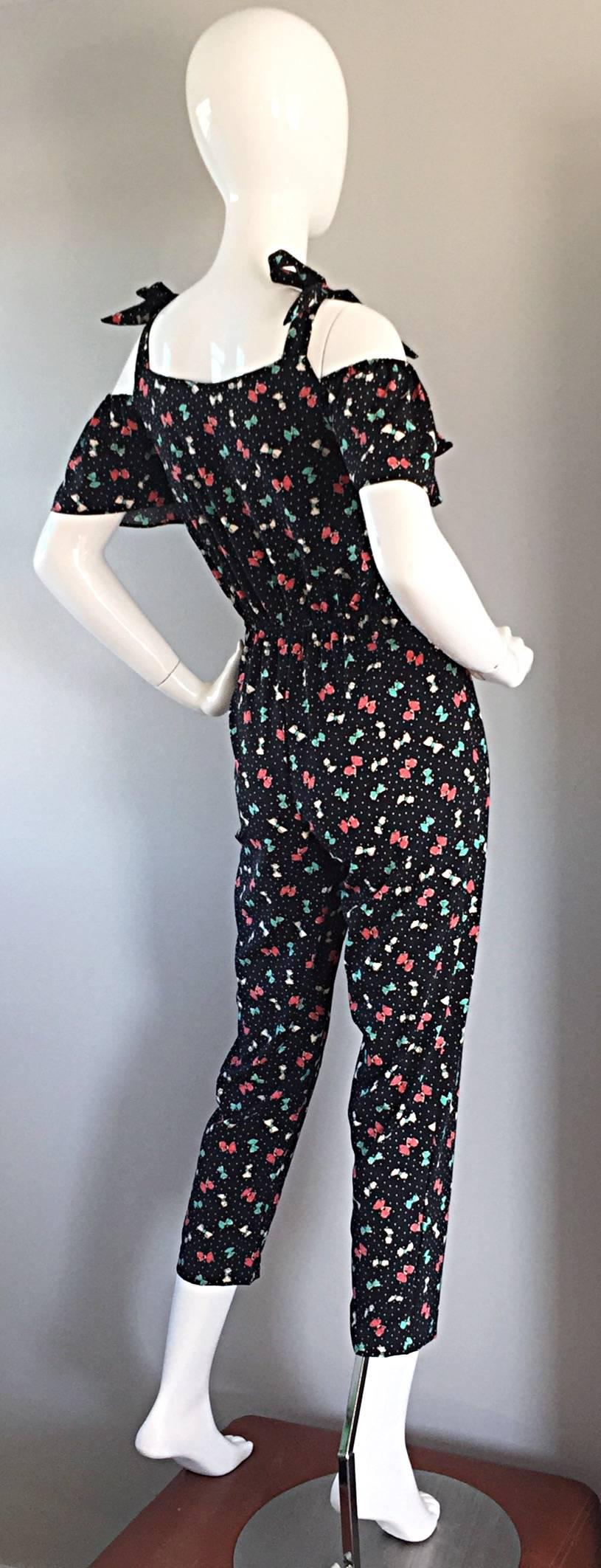 Incredible vintage 1980s does 1950s bombshell jumpsuit! Whimsical prints of colorful bows, with white pin-dot / polka dots, on a black background. Ruffles at bust. Can be worn a number of ways---with a halter neck, or with bows tied at each