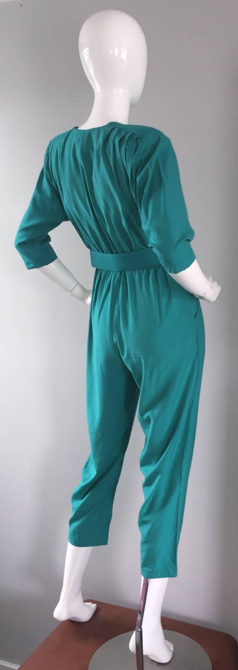 Chic 1980s teal green jumpsuit! Intricate pleating detail at shoulders. Slight dolman sleeves, to be worn by a variety of sizes. Detachable matching belt, with a large gold buckle. Perfect cropped length. 1980s does 1940s. In great condition.