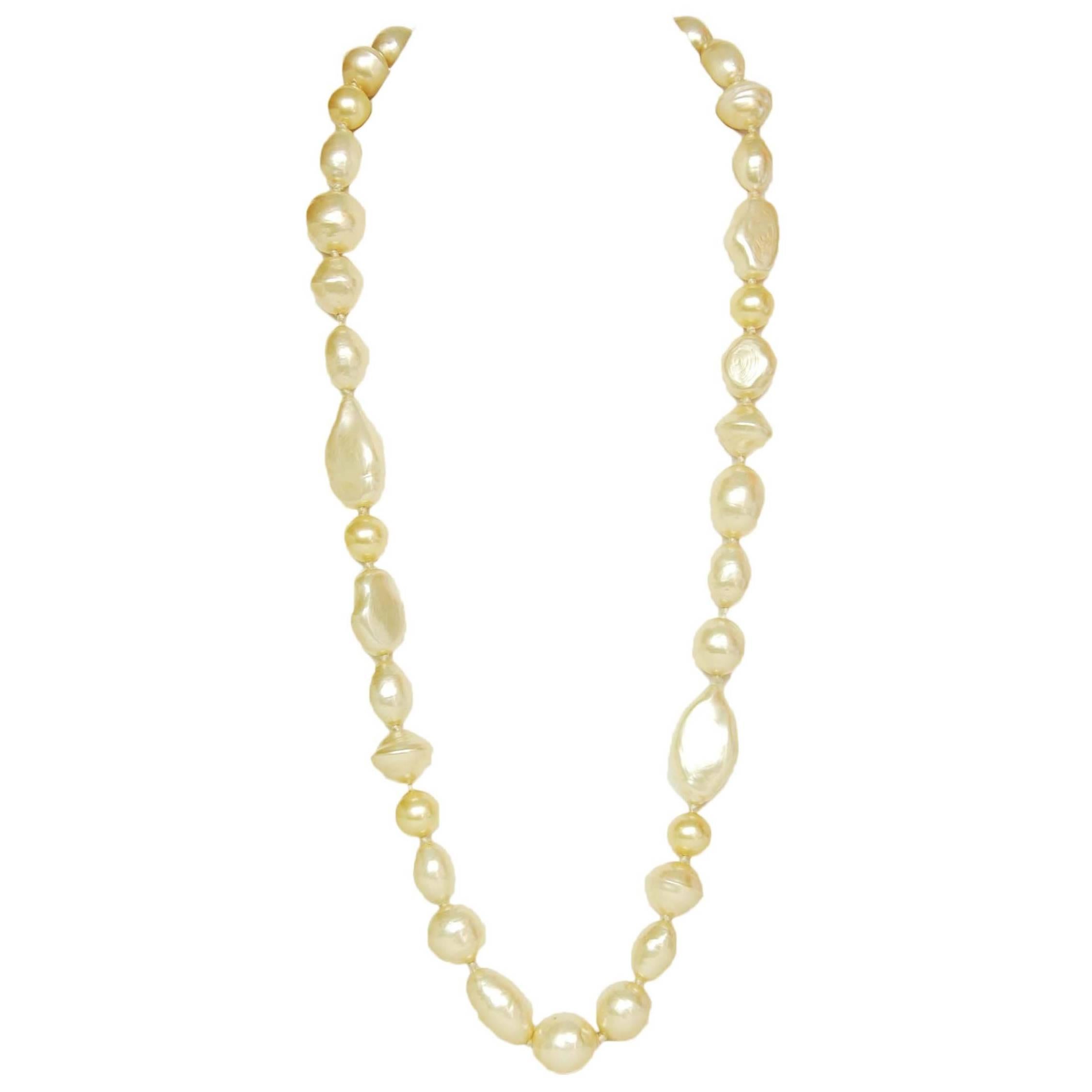 Chanel Vintage '83 Long Pearl Strand Necklace
Features different shaped faux pearls with red gripoix closure 

Year of Production: 1983
Color: Ivory, goldtone and red
Materials: Faux pearls, red gripoix and metal
Closure: Hook closure
Stamp: Chanel