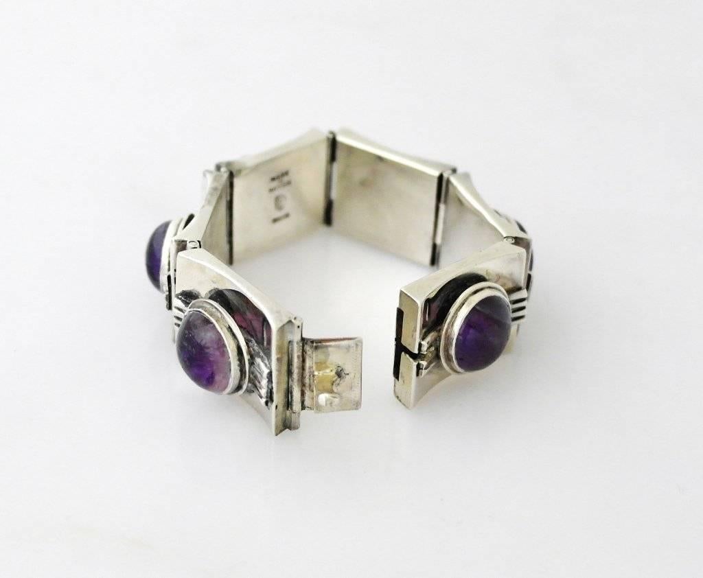 Being offered is a circa 1940 sterling silver bracelet by Fred Davis of Taxco, Mexico, of extravagant and decodesign, the rectangular striated panel links set with high-domed amethysts.  Each of the six links measure 1 inch by 1 1/8 inches.   In