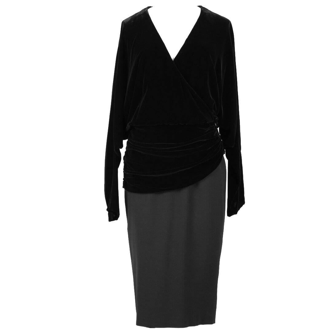 This dress features a black velvet wrap effect blousy cut bodice with a plunging neckline and a woolen fitted pencil skirt draped with gathered velvet at the hip area. The dropped-shoulder style top has long dolman sleeves that become narrow to the