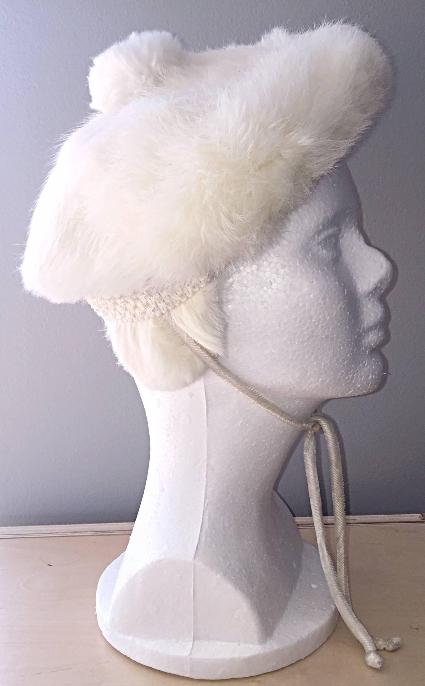 Chic 1960s rabbit fur beret, with large fur pom pom. Ear covers that can be left tucked in, or out for those extra cold days. Features a tie under the chin (in case it's windy). Fully lined. In great condition, and super soft! Will fit most sizes,