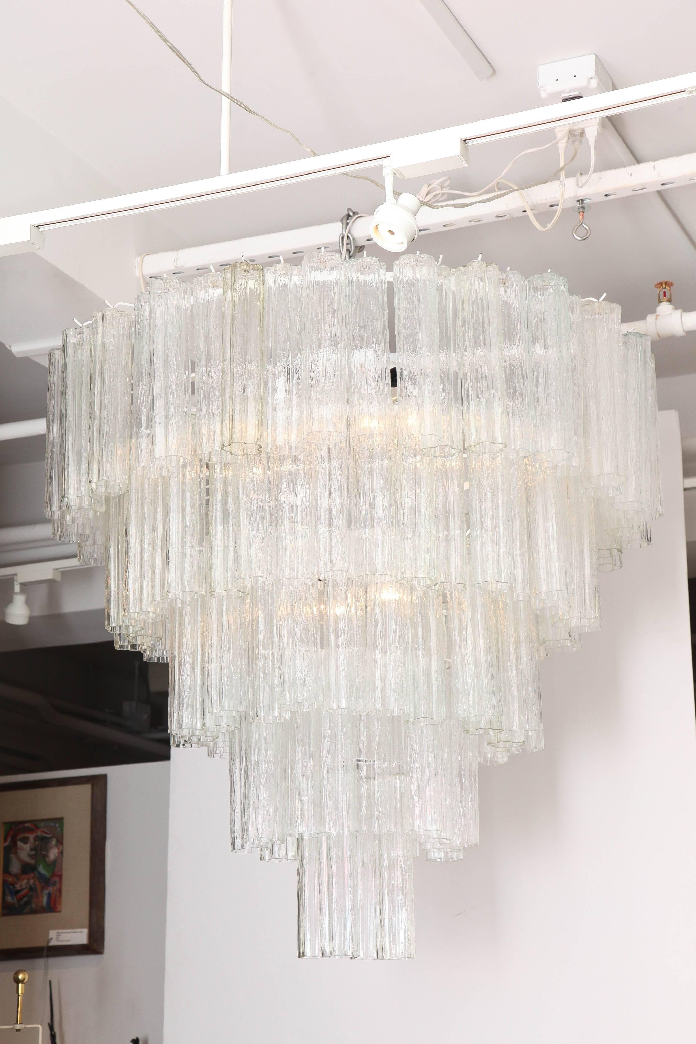 Large-scale Italian midcentury five-tier chandelier with textured glass tronchi tubes suspended on a white enameled frame with brass chain and canopy. Rewired for use in the USA. With chain measures 48