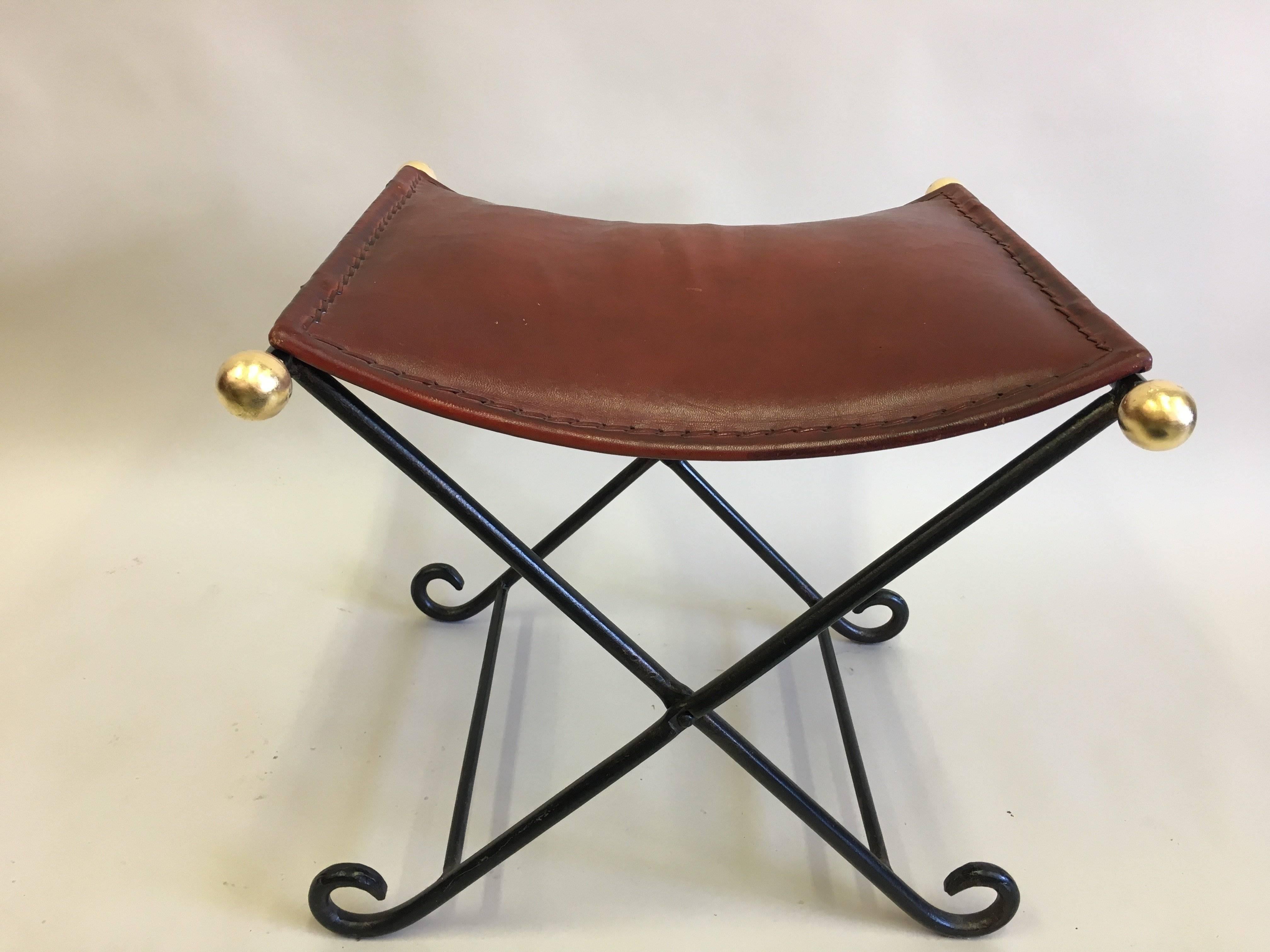 Pair of French Mid-Century Modern Neoclassical hand-wrought iron benches with hand-stitched leather seats attributed to Raymond Subes.

The pieces feature gilt iron balls and detailing.