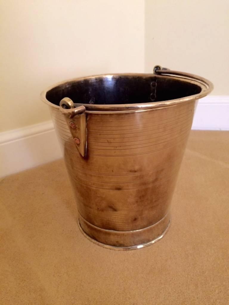 A brass pail or bucket,  England, circa 1780.
Measures: Height: 12 inches (with handle erect 19 inches),
diameter: 11.5 inches.

Probably a milk pail from a model dairy. Made with a single sheet of seamed brass, the folding handle held in place