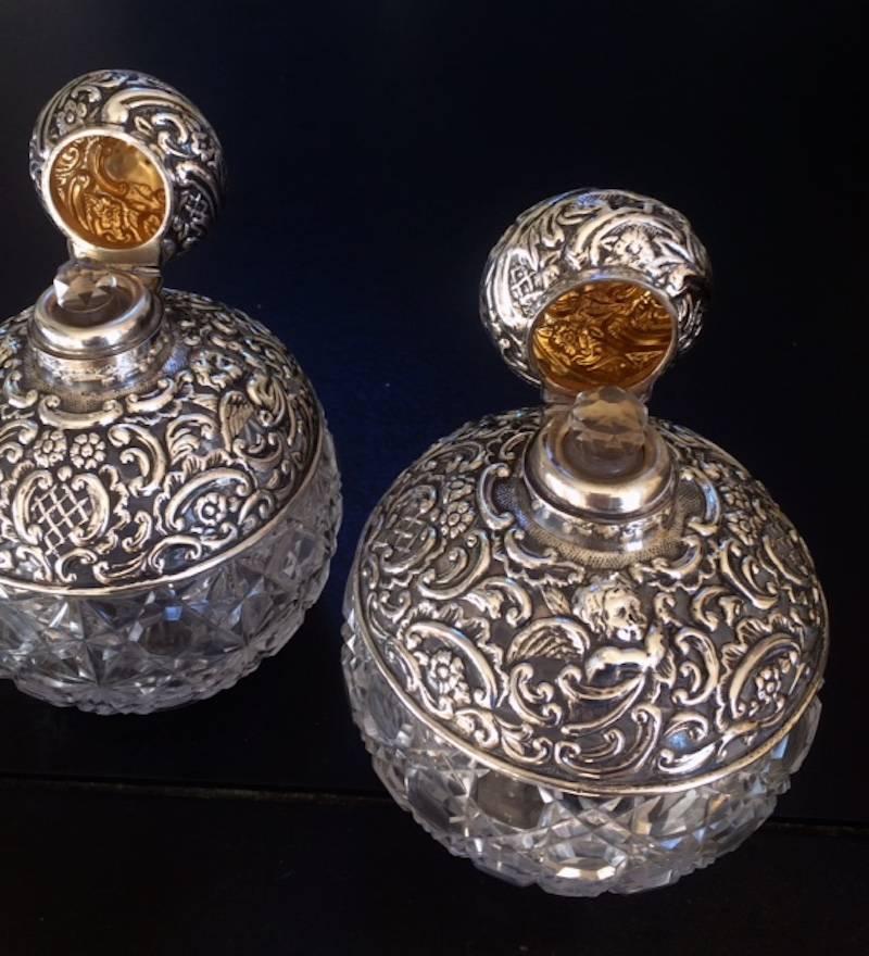 A pair of large cut-glass perfume bottles mounted in silver. Made by Mathew John Jessop, Birmingham, 1907.

The pierced and repousse silver mounts are decorated with Rococo 