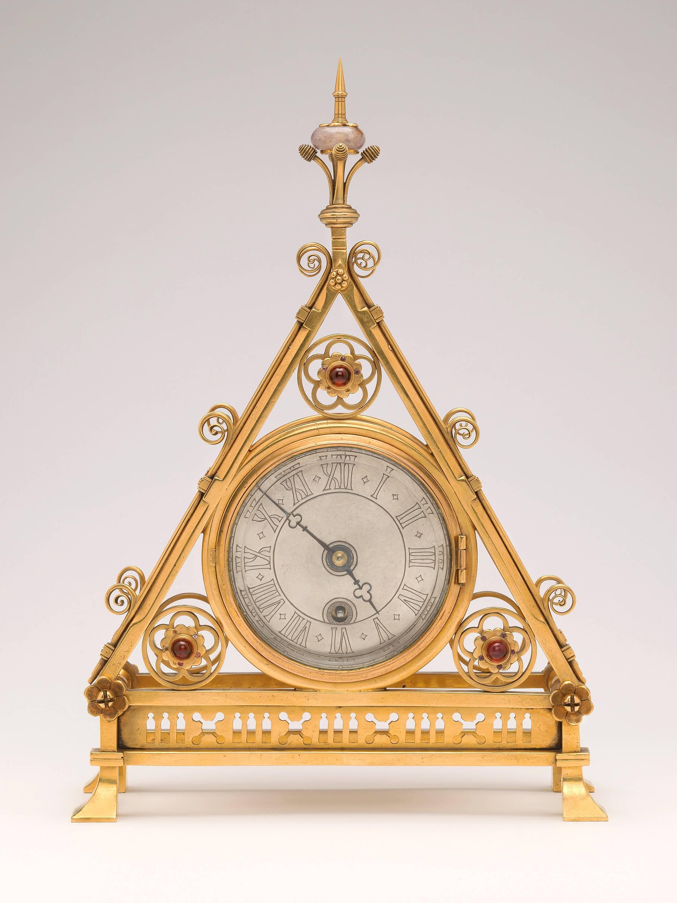 This particularly fine gothic architectural model, retains its original face and hands. The finial is mounted with Derbyshire Blue John. The dial is surrounded by three roundels of cinquefoil design, the centres are mounted with red cabochon glass.