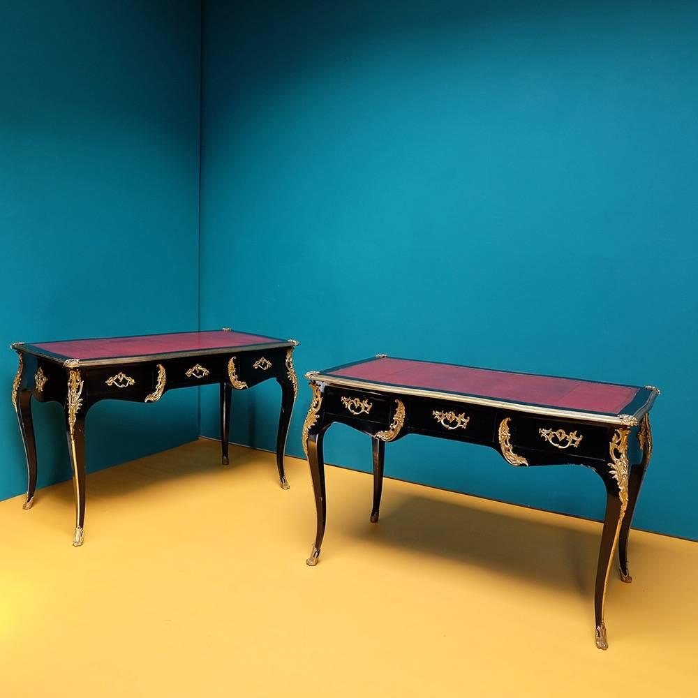 Pair of ebonized lacquered desks with gilt ormolu mouldings and tooled red Moroccan leather tops.
