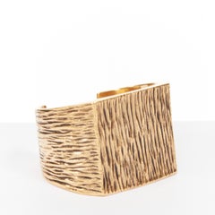 Pulsera cuadrada tipo manguito de SAINT LAURENT, en tono dorado envejecido, con textura de corteza de árbol