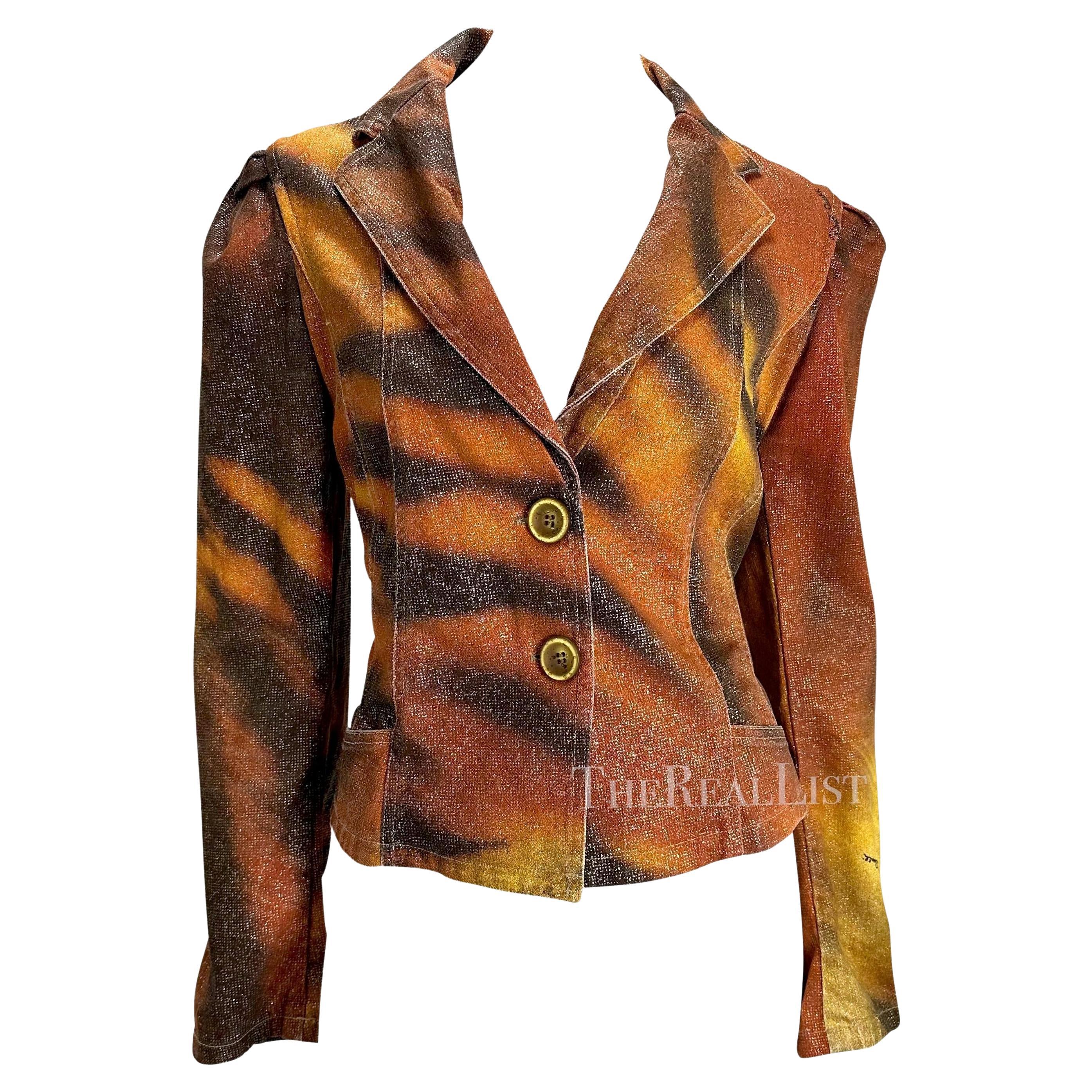 Presentamos un blazer tigre de Roberto Cavalli. De la colección Otoño/Invierno 2000, esta chaqueta luce audazmente el icónico estampado de tigre de Cavalli. Esta feroz chaqueta presenta un cuerpo recortado, cierre de botones y hombros ligeramente