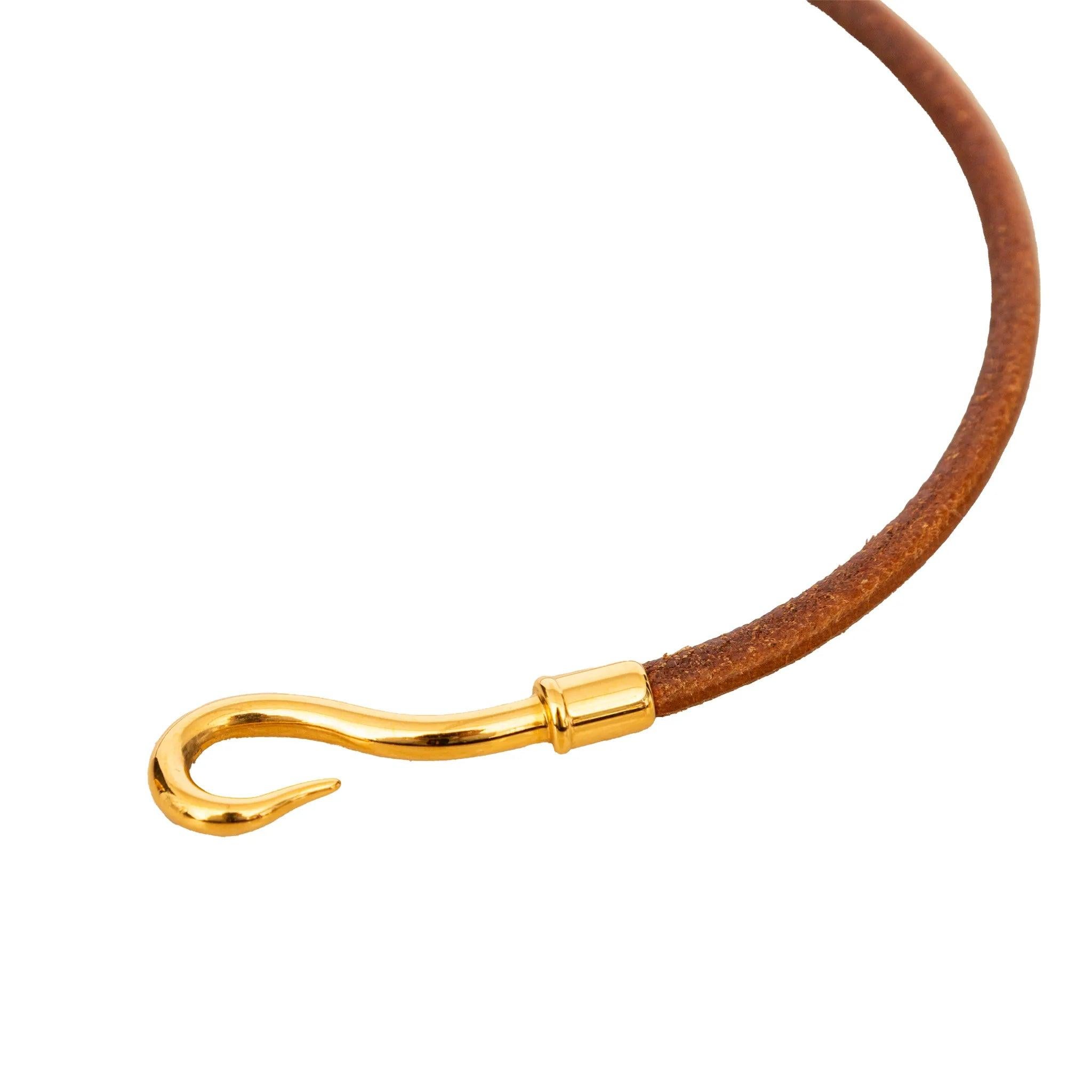 Bracciale Hermès Jumbo Hook in pelle marrone con chiusura a gancio placcata oro. Versatile e senza tempo: indossalo come bracciale, impilato o come un elegante girocollo. Inclusione: scatola.
 Osservazioni: alcuni segni di usura. 
 Misure: