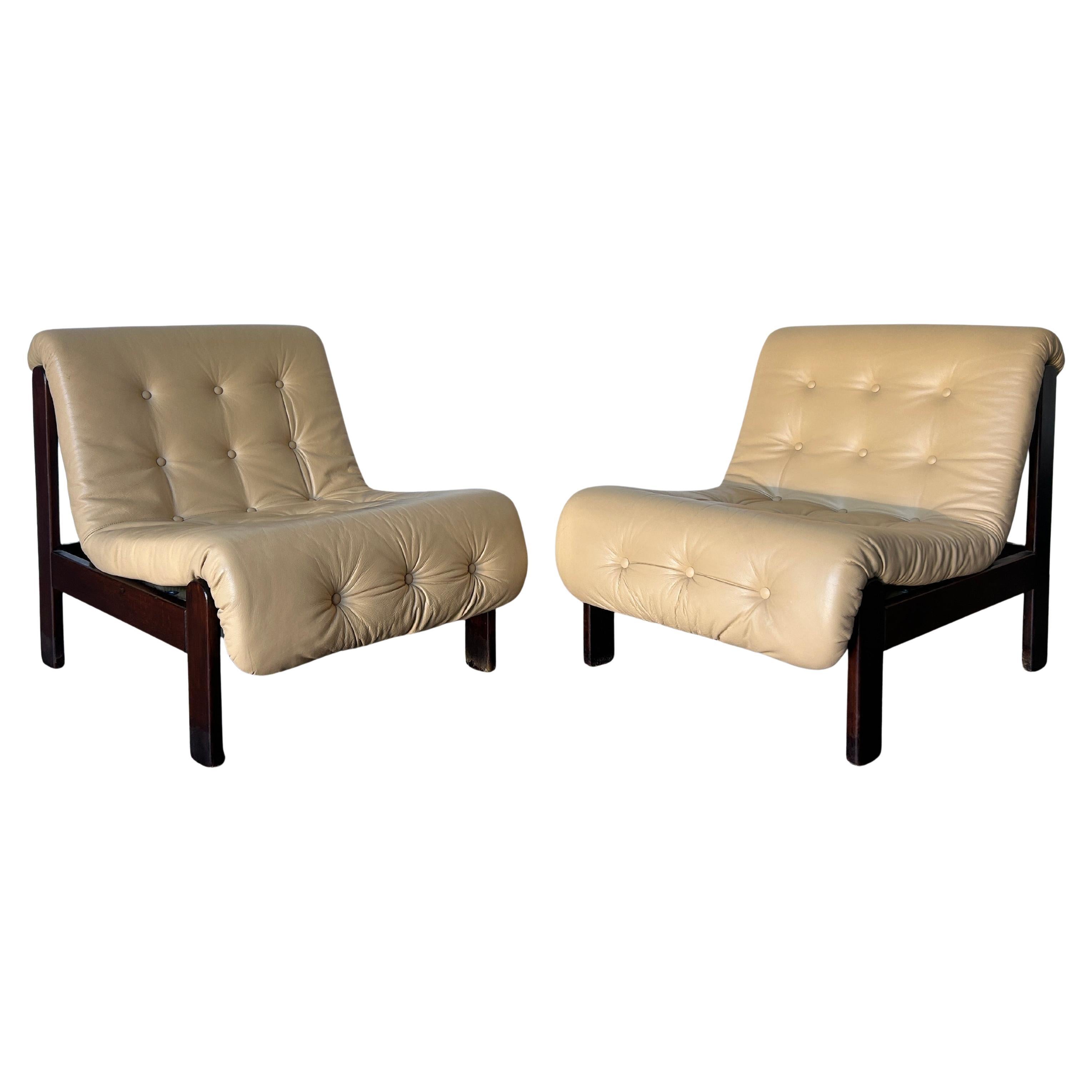 Pair of tufted armless leather lounge chairs with wood frames