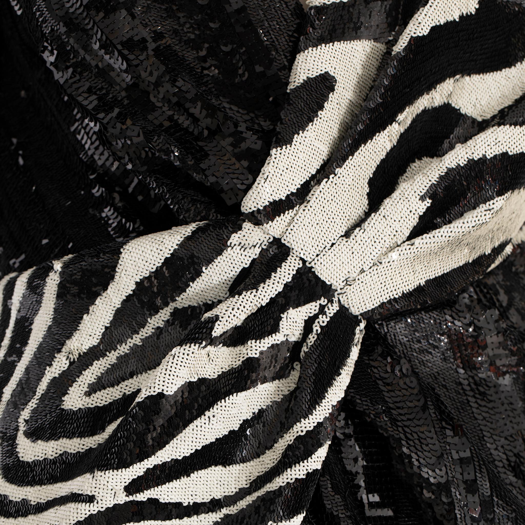 La robe de cocktail à manches longues Saint Laurent by Hedi Slimane est réalisée en laine noire recouverte de divers paillettes noires. Elle est faussement enveloppante, froncée sur le devant, dotée d'une encolure en V, d'épaules paddées, d'un