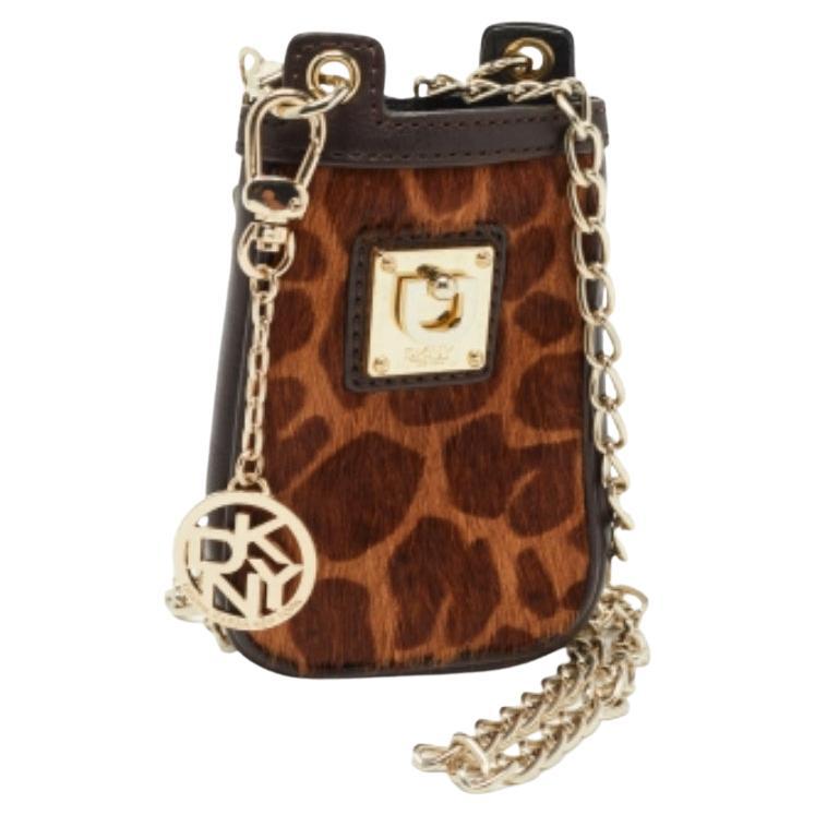 Questo accessorio DKNY è un'ottima scelta per portare con sé il telefono e le carte di credito. È realizzata in pelo di vitello con stampa leopardata e sfoggia una maglia a catena e un accento con marchio sul davanti.