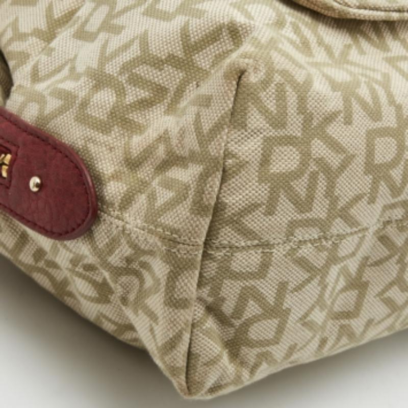 La silhouette semplice e l'uso di tela e pelle Monogram per l'esterno esaltano il fascino di questa borsa DKNY. Presenta doppi manici, finiture dorate e un interno foderato in tessuto.