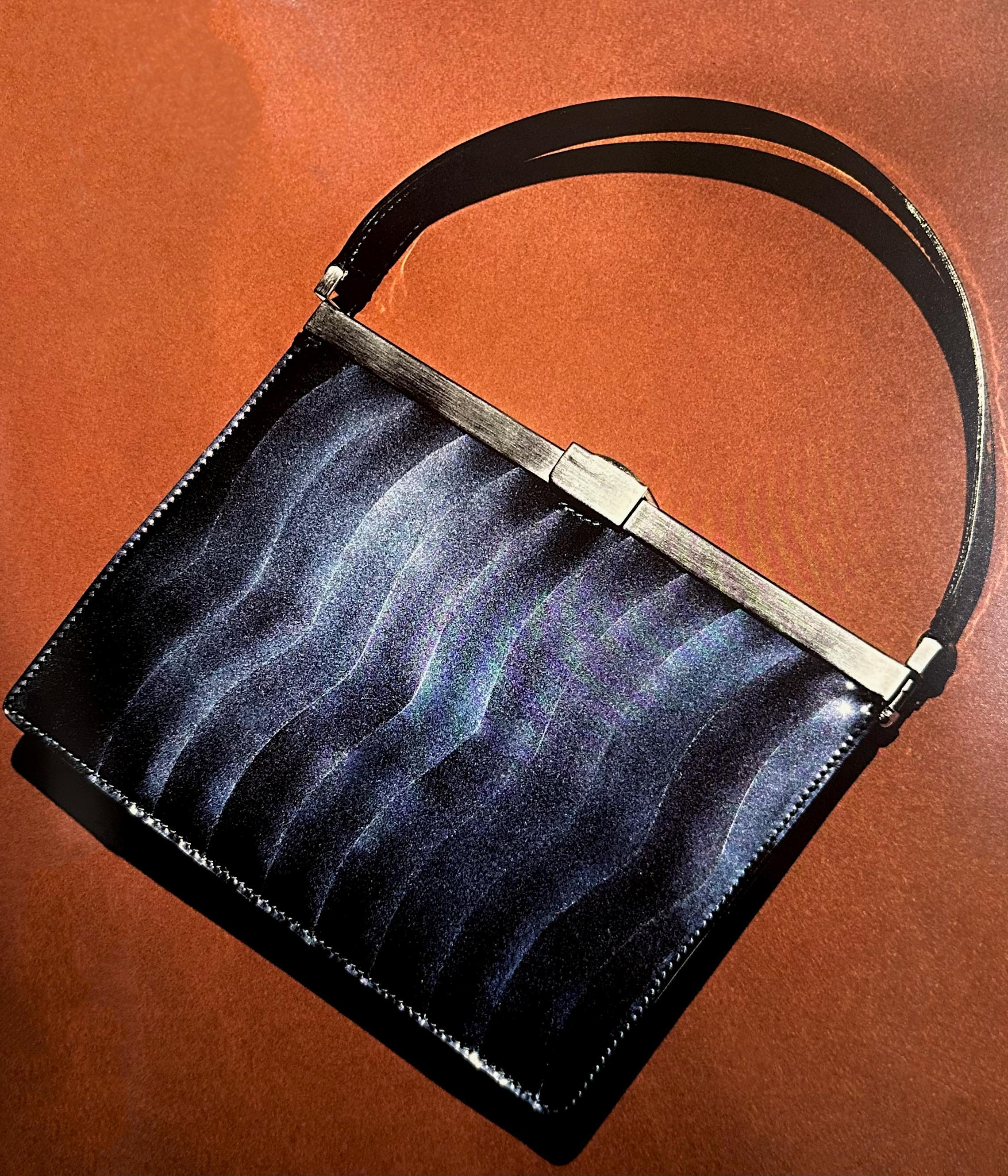 This mini bag from Giorgio Armani's Fall/Winter 2000 collection showcases a structured, frame-top silhouette in high-shine black patent leather. The bag features a distinct scallop panel design on the front and back, creating a textured, wave-like