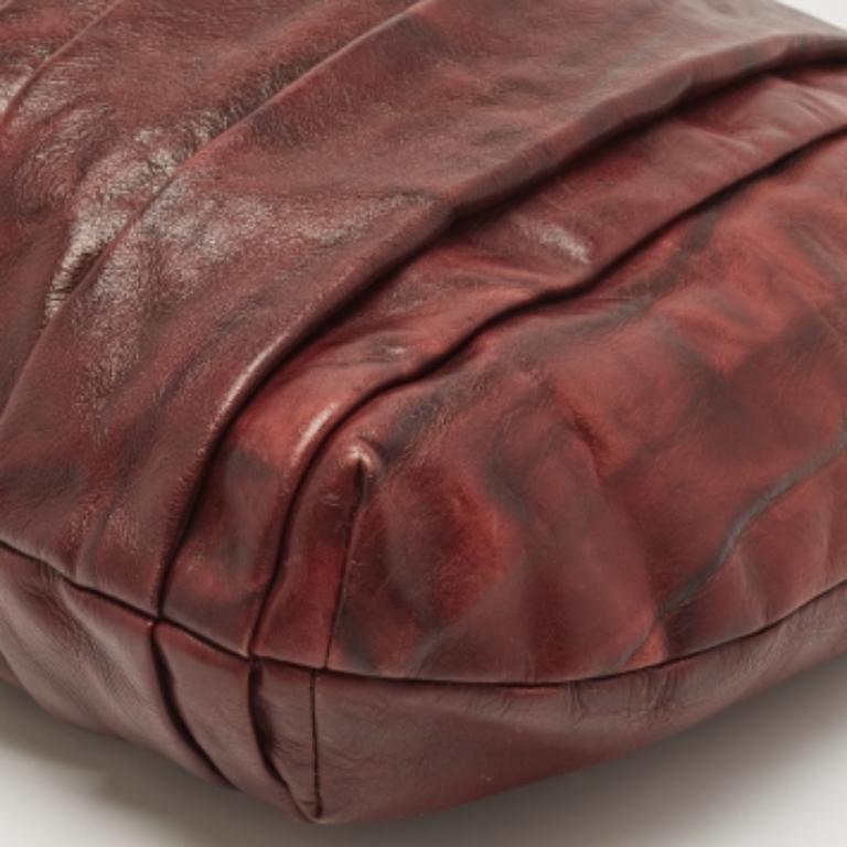 Questa borsa Dkny ti aiuterà a creare un look elegante e senza sforzo. Realizzata in pelle, è di colore bordeaux. Ha un esterno plissettato e si regge con un'unica maniglia. Si apre per rivelare un interno foderato di raso che offre spazio