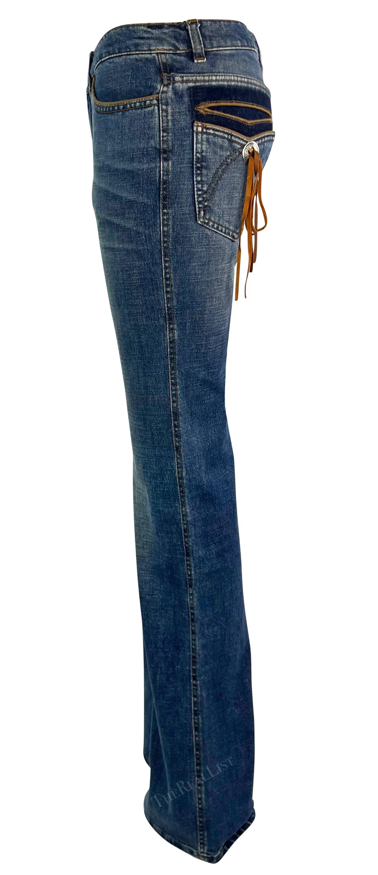 Presenting a pair of light-wash Roberto Cavalli jeans. From 2003, these lightly flared jeans are adorned with a silver-tone metal button and suede fringe at the rear pockets. These American West-inspired Robert Cavalli jeans are made complete with